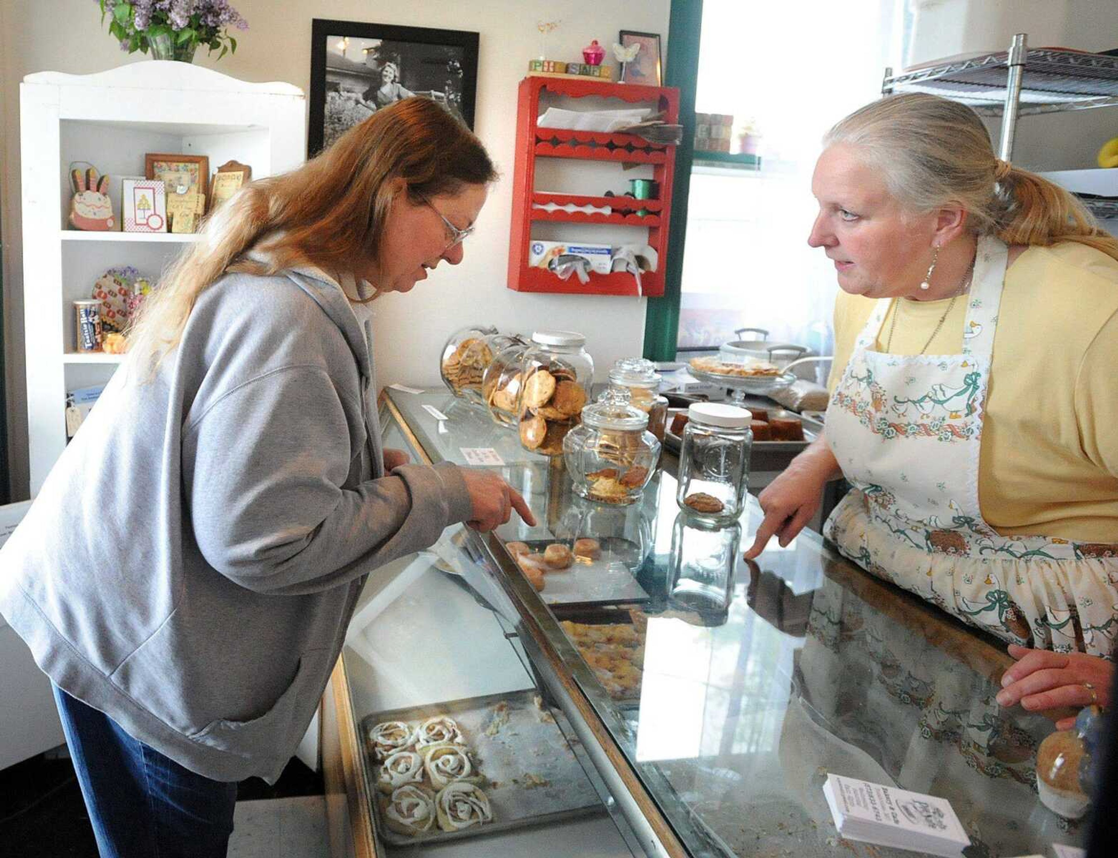 Peggy Luehrs picks out a slice of pineapple-coconut coffee cake from Sharon Penrod&#8217;s case of baked goods Sunday at her Pocahontas bakery and cafe, the Pie Safe. The Pie Safe was one of many stops along the 23rd annual Mississippi River Valley Scenic Drive. (Laura Simon)