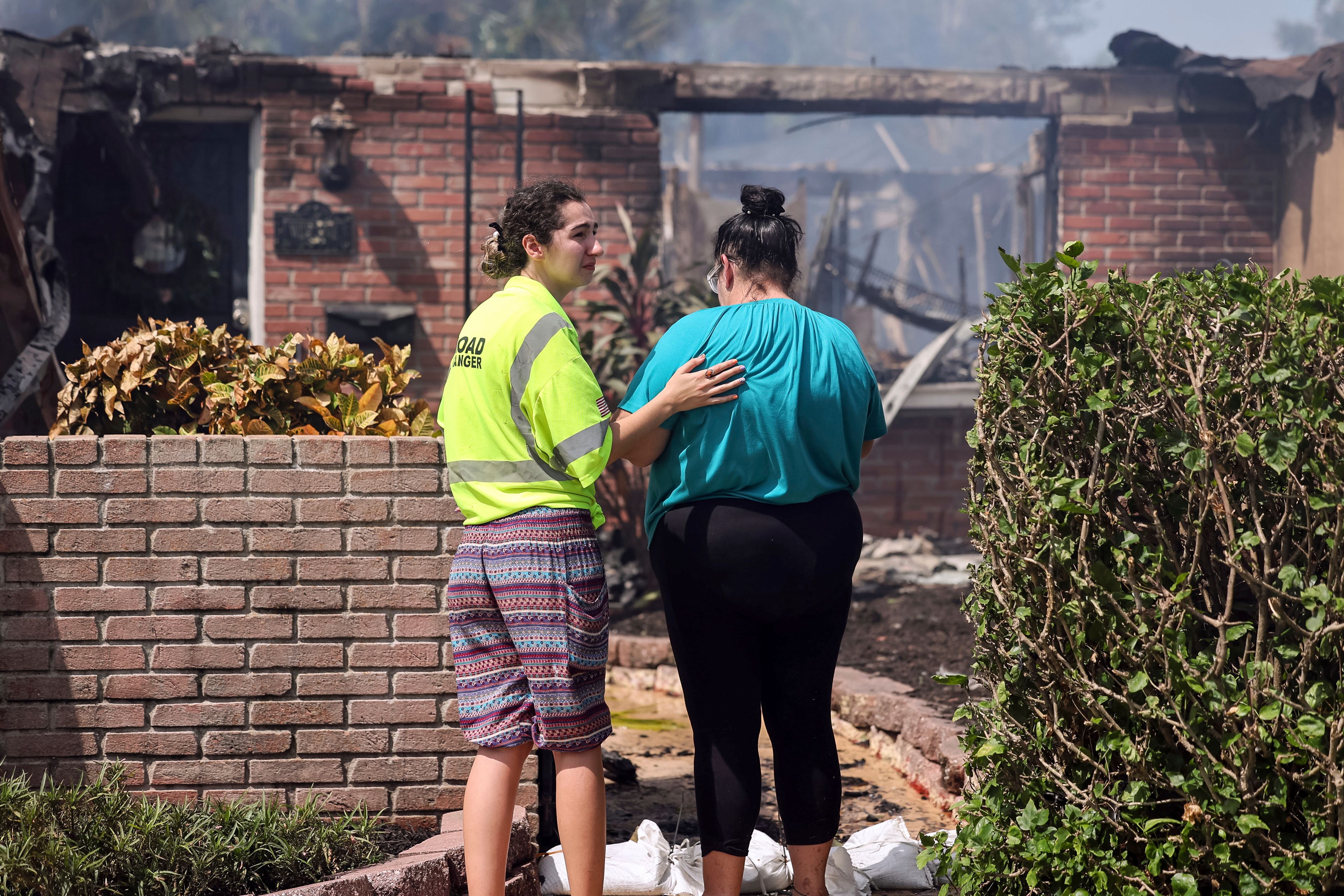 Faith Cotto comforts her mother Nancy as they look at the remains of their home which burned during the flooding from Hurricane Helene in the Shore Acres neighborhood Friday, Sept. 27, 2024, in St. Petersburg, Fla. (AP Photo/Mike Carlson)