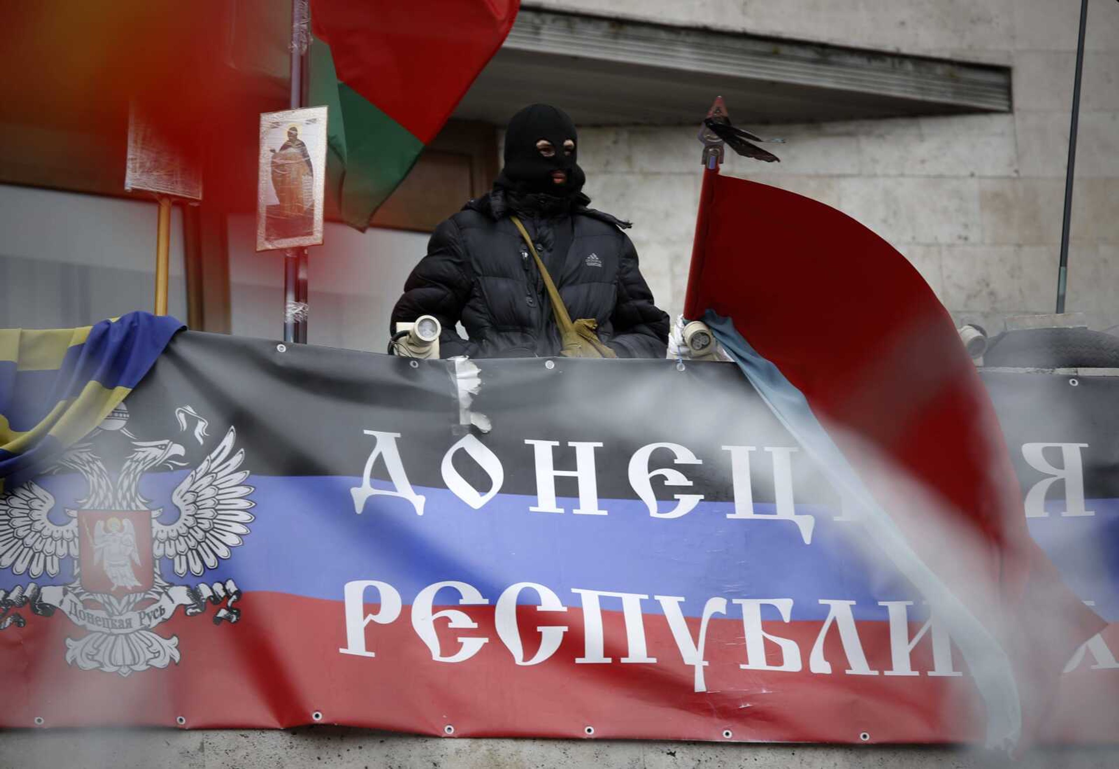 A masked pro-Russian activist looks from a balcony of the regional administration building decorated with a banner reading &#8220;Donetsk Republic&#8221; in Donetsk, Ukraine, on Saturday. (Max Vetrov ~ Associated Press)