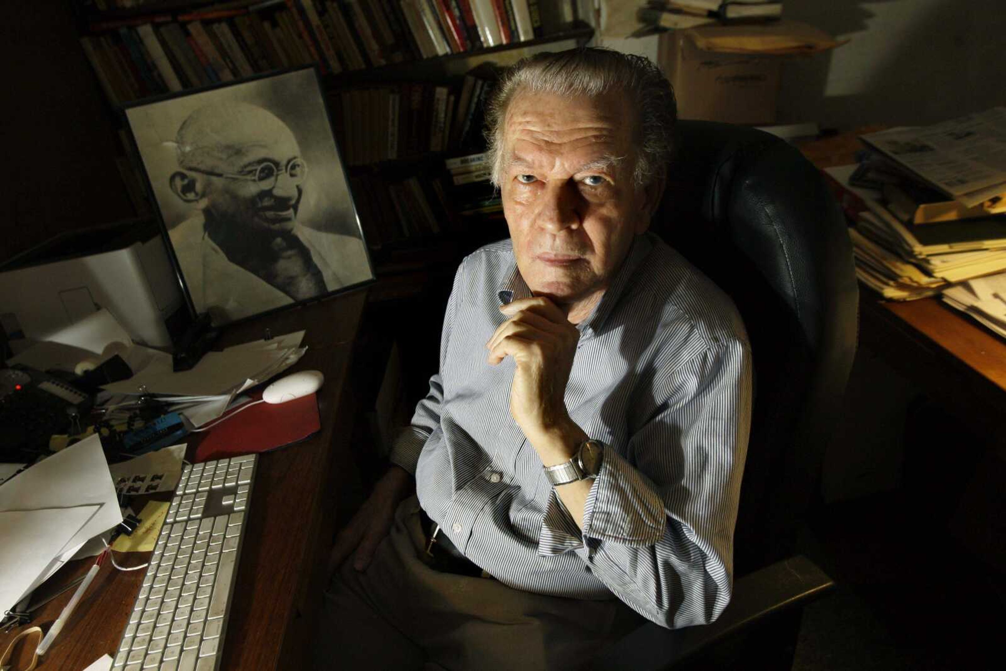 Gene Sharp poses at his office in Boston Thursday, June 25, 2009 with a photo of Gandhi at rear. Iranian protesters wondering what to do next are being encouraged to turn to the same source that helped drive a decade of nonviolent revolutions in eastern Europe: a how-to guide to toppling dictatorships written by an aging American academic you've probably never heard of. But the Iranian regime definitely knows Gene Sharpe's name and released a fictionalized video last year warning he and other Americans were planning a "velvet revolution" in Iran. (AP Photo/Elise Amendola)