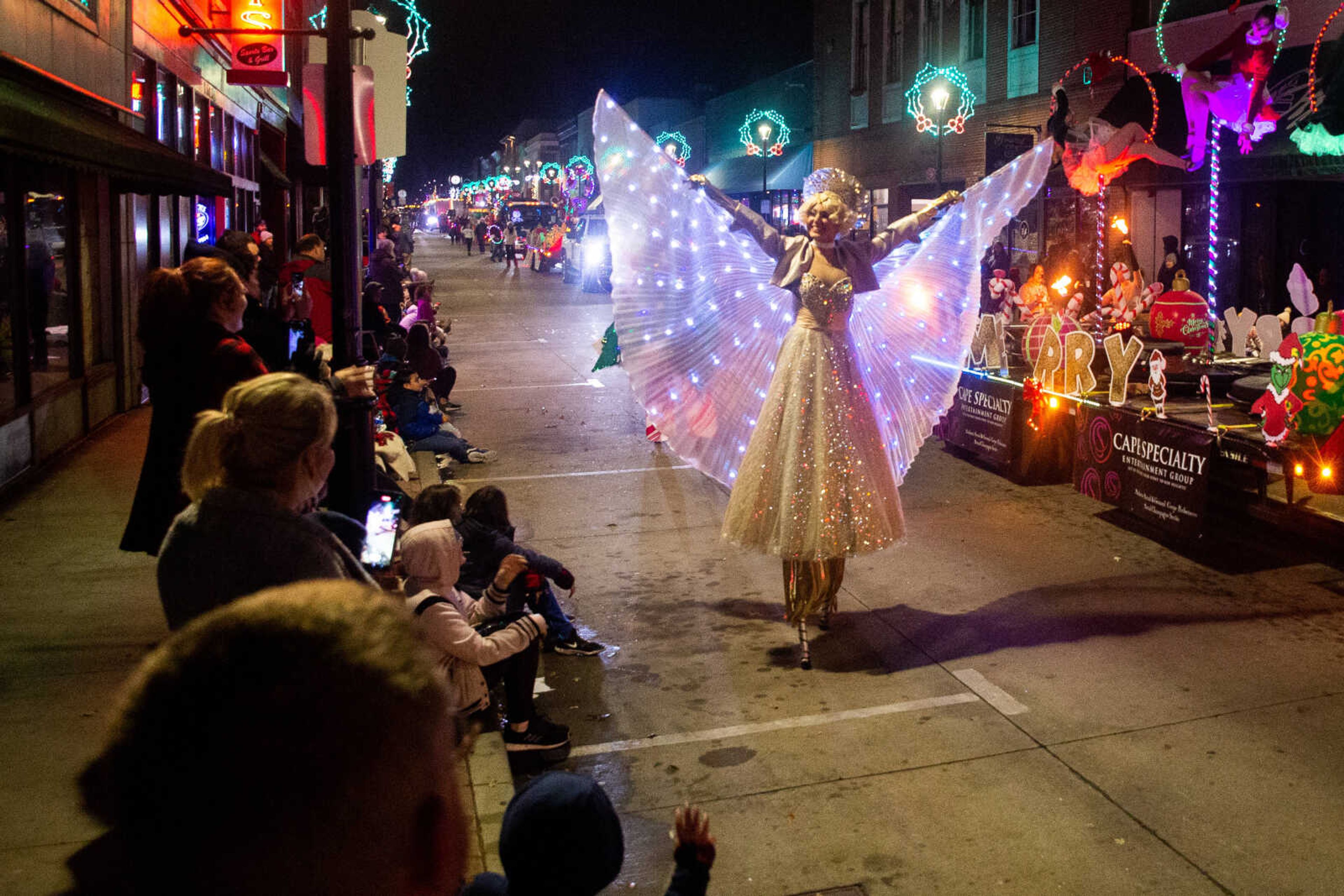 Lily Hetz raises her light-up wings in the air as she walks on stilts in the Parade of Lights on Sunday, Nov. 27 in downtown Cape Girardeau.