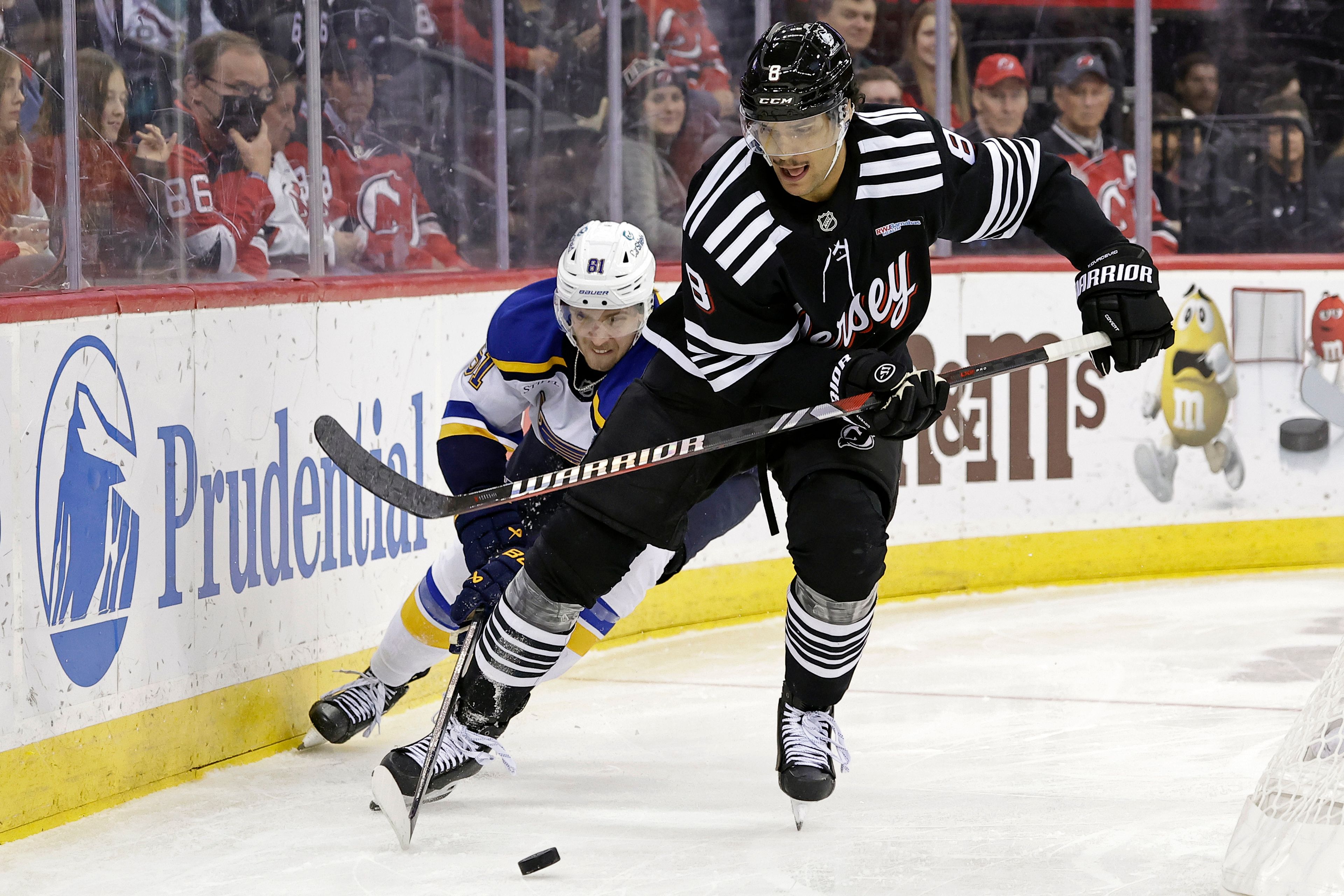 New Jersey Devils defenseman Johnathan Kovacevic (8) battles for the puck with St. Louis Blues center Dylan Holloway during the third period of an NHL hockey game Wednesday, Nov. 27, 2024, in Newark, N.J. St. Louis won 3-0. (AP Photo/Adam Hunger)