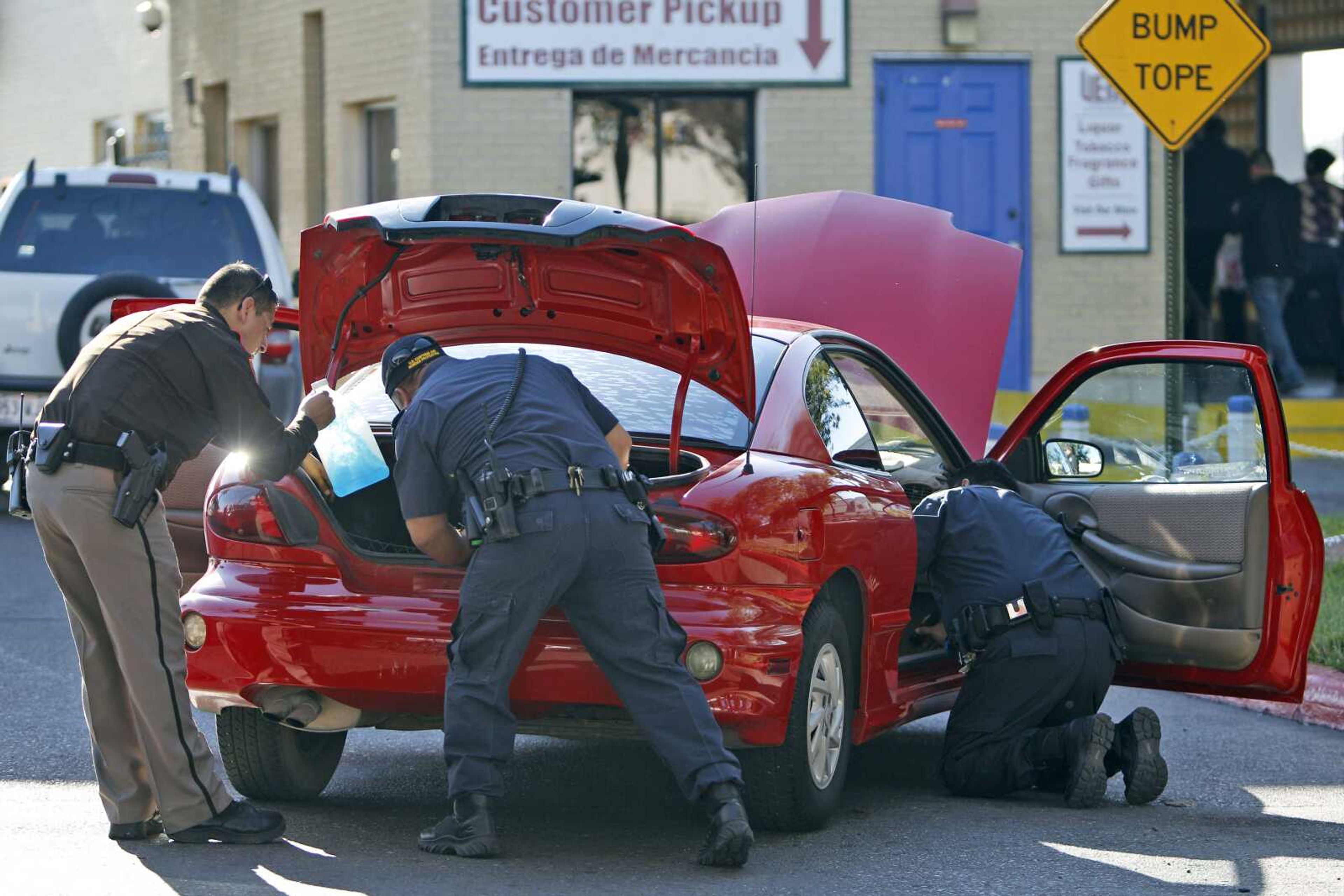 U.S. Customs and Border Protection agents and a local sheriff's deputy inspect a car heading southbound from the U.S. to Mexico on Dec. 9 in Brownsville, Texas. Customs agents and local law enforcement are trying to stem smuggling of guns and cash from the U.S. to Mexico. (Associated Press file)