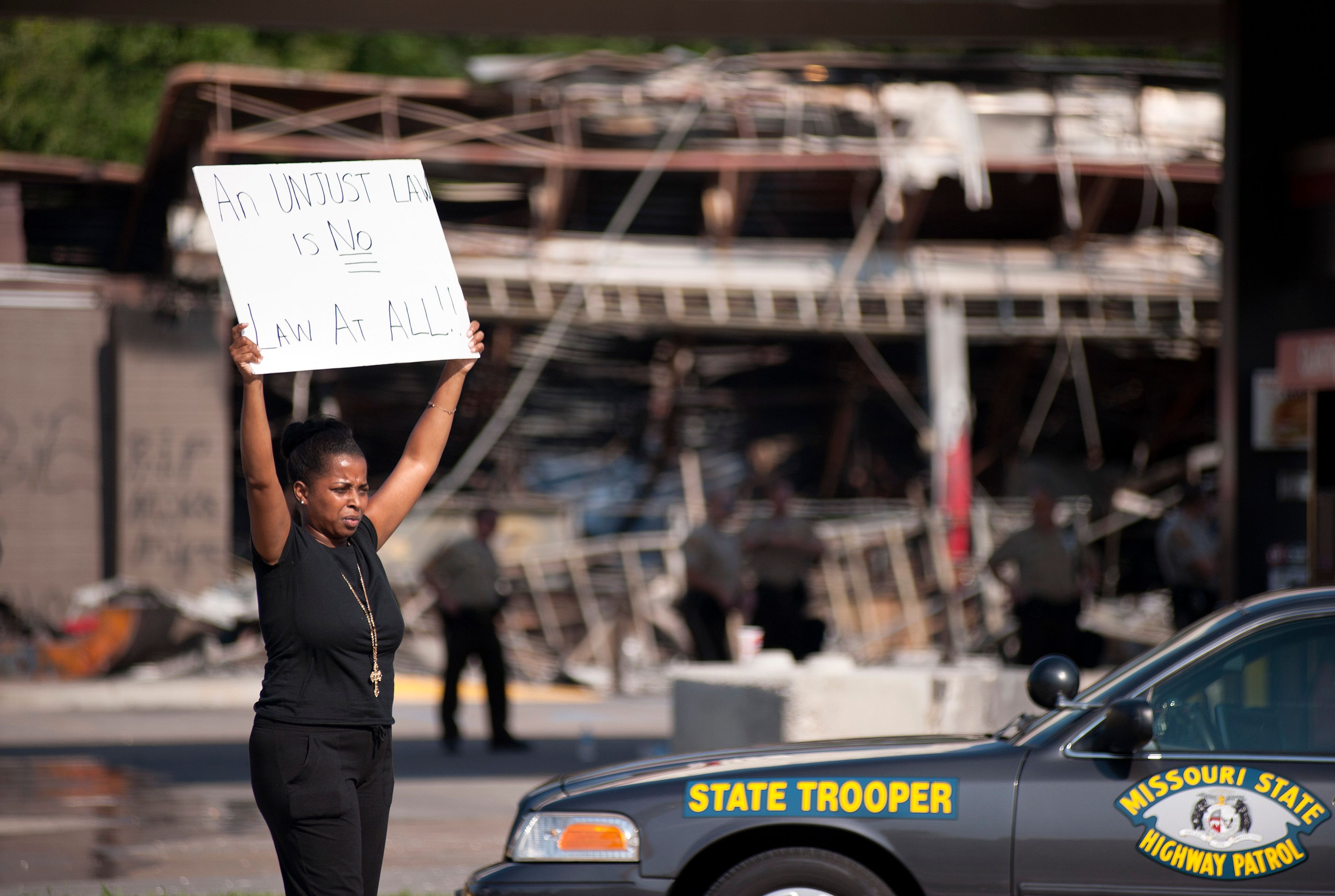 FILE - Protesters appeal to motorists for support while rallying on Aug. 11, 2014 in front of the QT gas station in Ferguson, Mo. that was looted and burned during rioting overnight that followed a candlelight vigil honoring 18-year-old Michael Brown, who was shot on Aug. 9, 2014 by Ferguson police officers. (AP Photo/Sid Hastings)