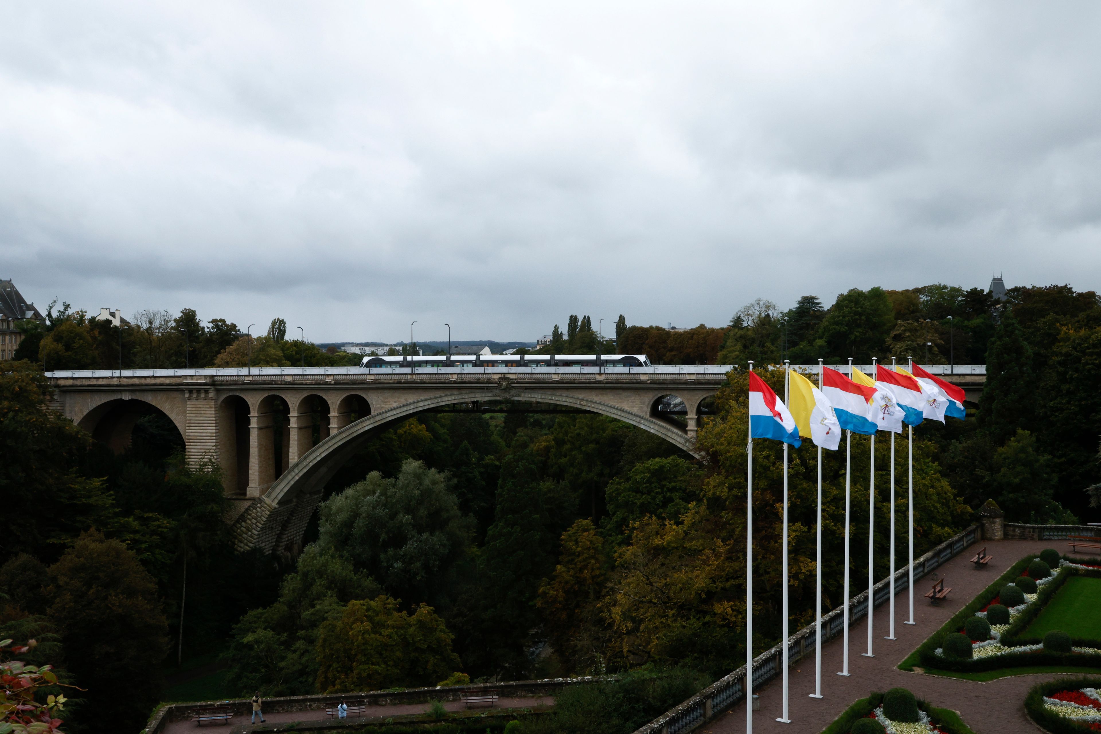 A tramway crosses the iconic Adolphe Bridge where flags of the Vatican and Luxembourg are seen waving in the surrounding gardens on the day before Pope Francis' trip to Luxembourg and Belgium, Wednesday, Sept. 25, 2024, (AP Photo/Omar Havana)