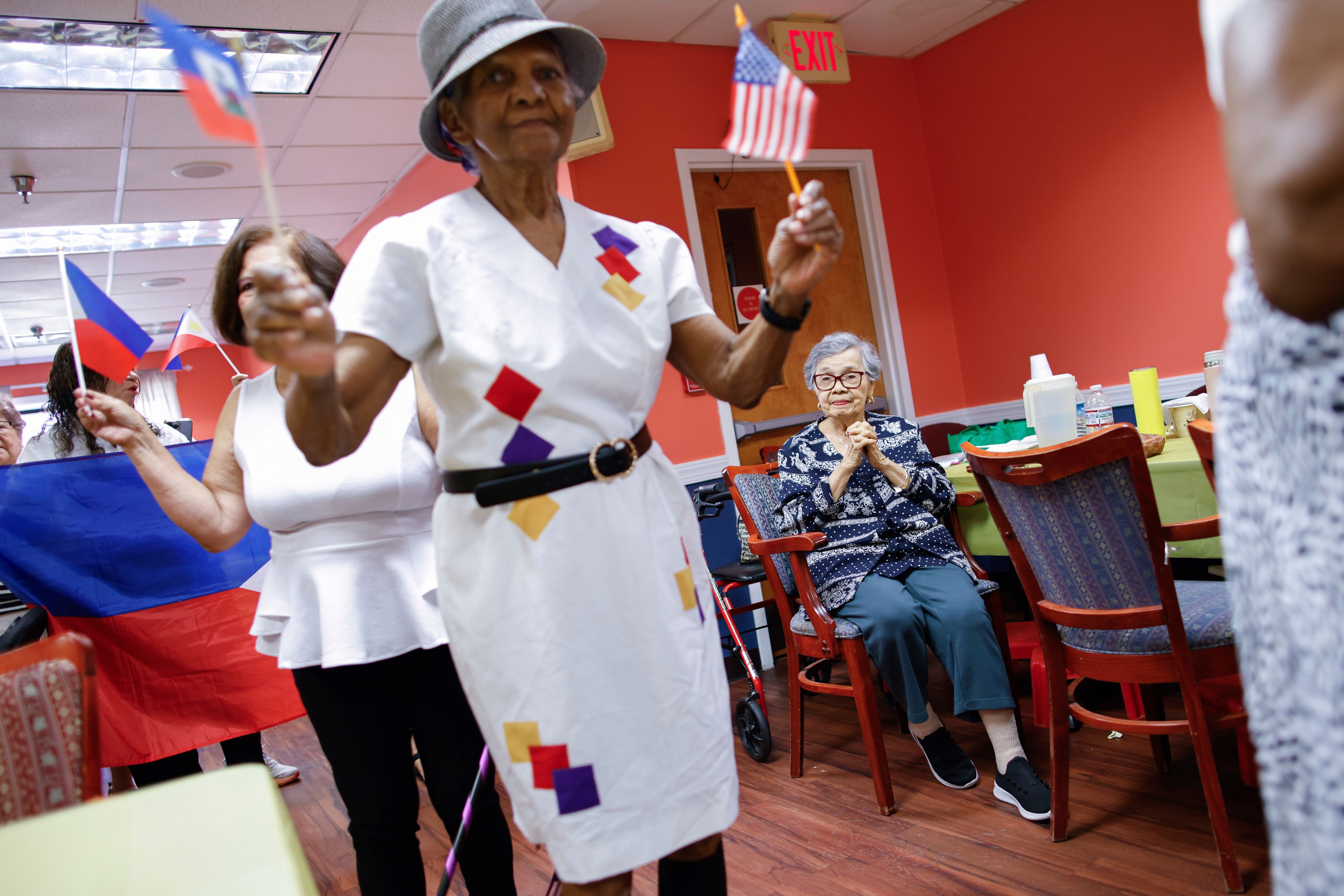 A woman from Haiti holds flags during a multicultural parade at Sunshine Adult Day Center in Bergenfield, N.J., Monday, Aug. 26, 2024. (AP Photo/Kena Betancur)