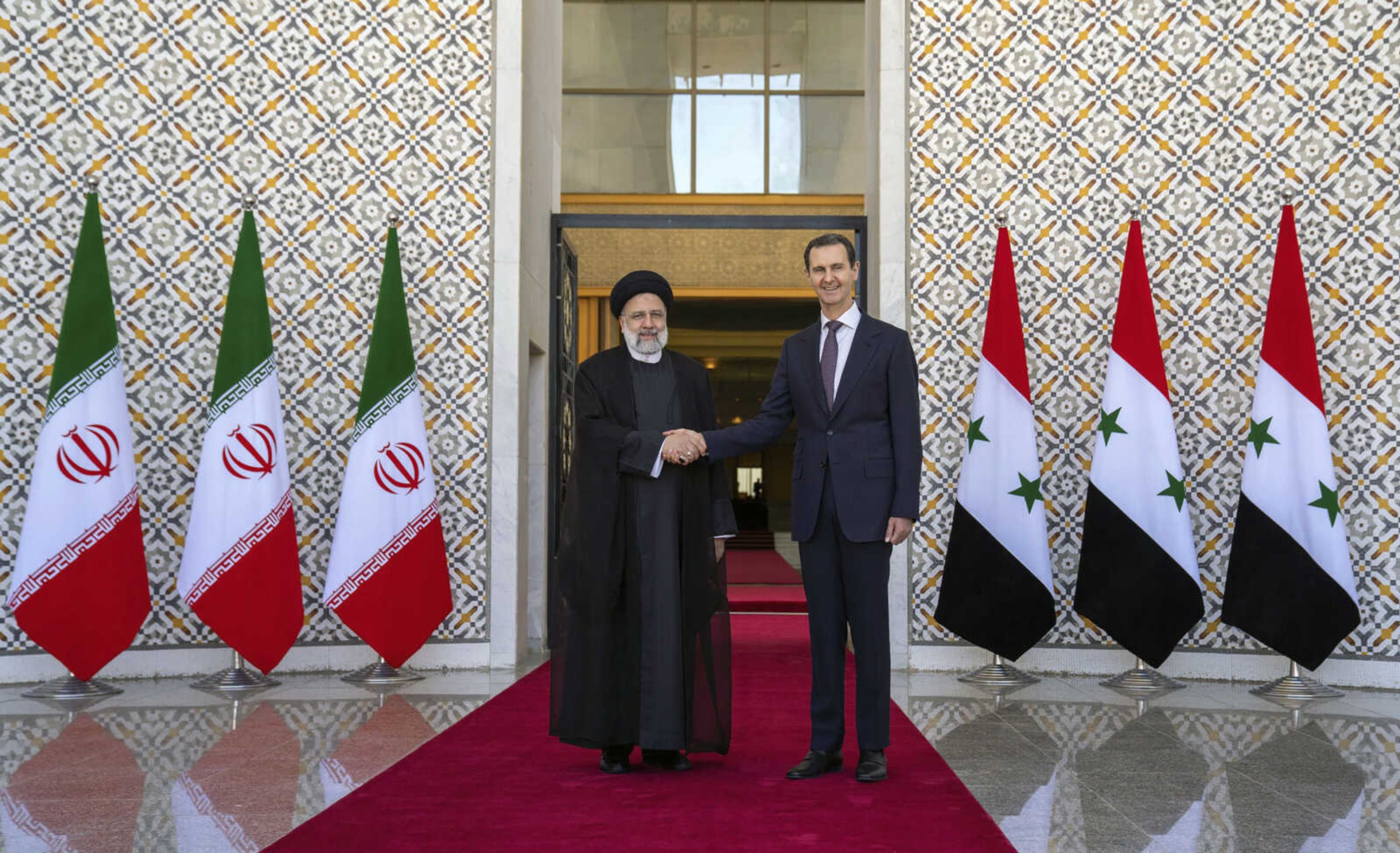 In this photo released by the official Facebook page of the Syrian Presidency, Syrian President Bashar Assad, right, shakes hands with Iranian President Ebrahim Raisi in Damascus, Syria, Wednesday, May 3, 2023. Iranian President Raisi Wednesday met Syrian President Assad in Damascus in a bid to boost cooperation between the two allies, state media reported. (Syrian Presidency via Facebook via AP)