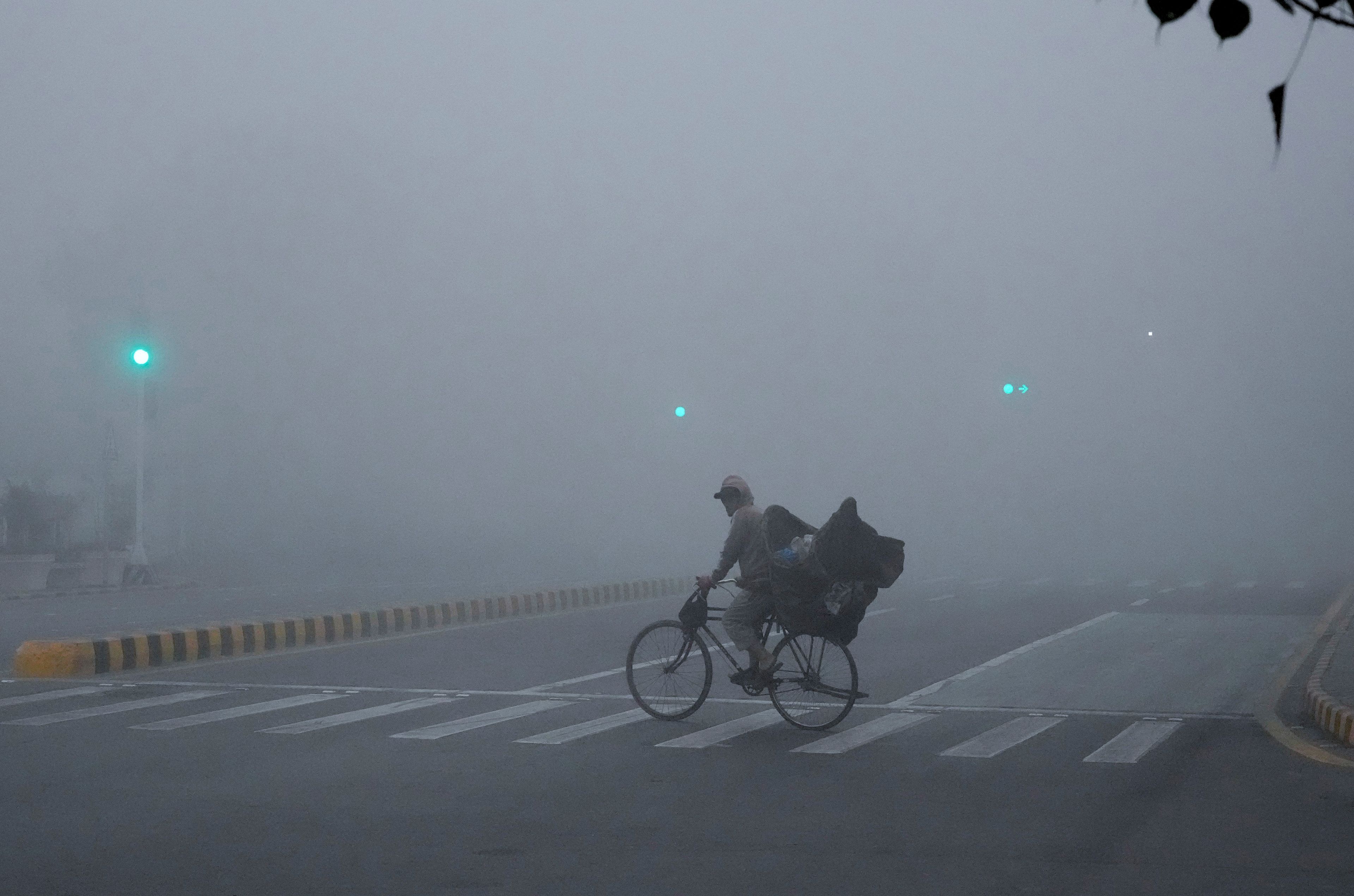 A cyclist crosses a road as smog envelopes the area of Lahore, Pakistan, Thursday, Nov. 14, 2024. (AP Photo/K.M. Chaudary)