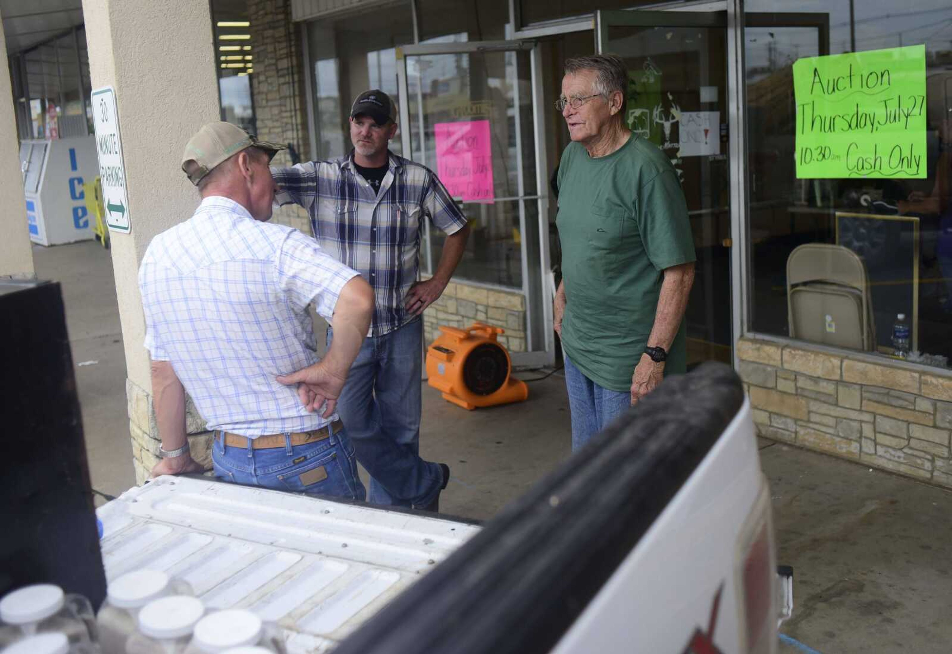 From left, Haven Willis, Mark Yount and Jim Foutz hang outside of Foutz's Fishing and Hunting Shop during the closing auction Thursday in Cape Girardeau.