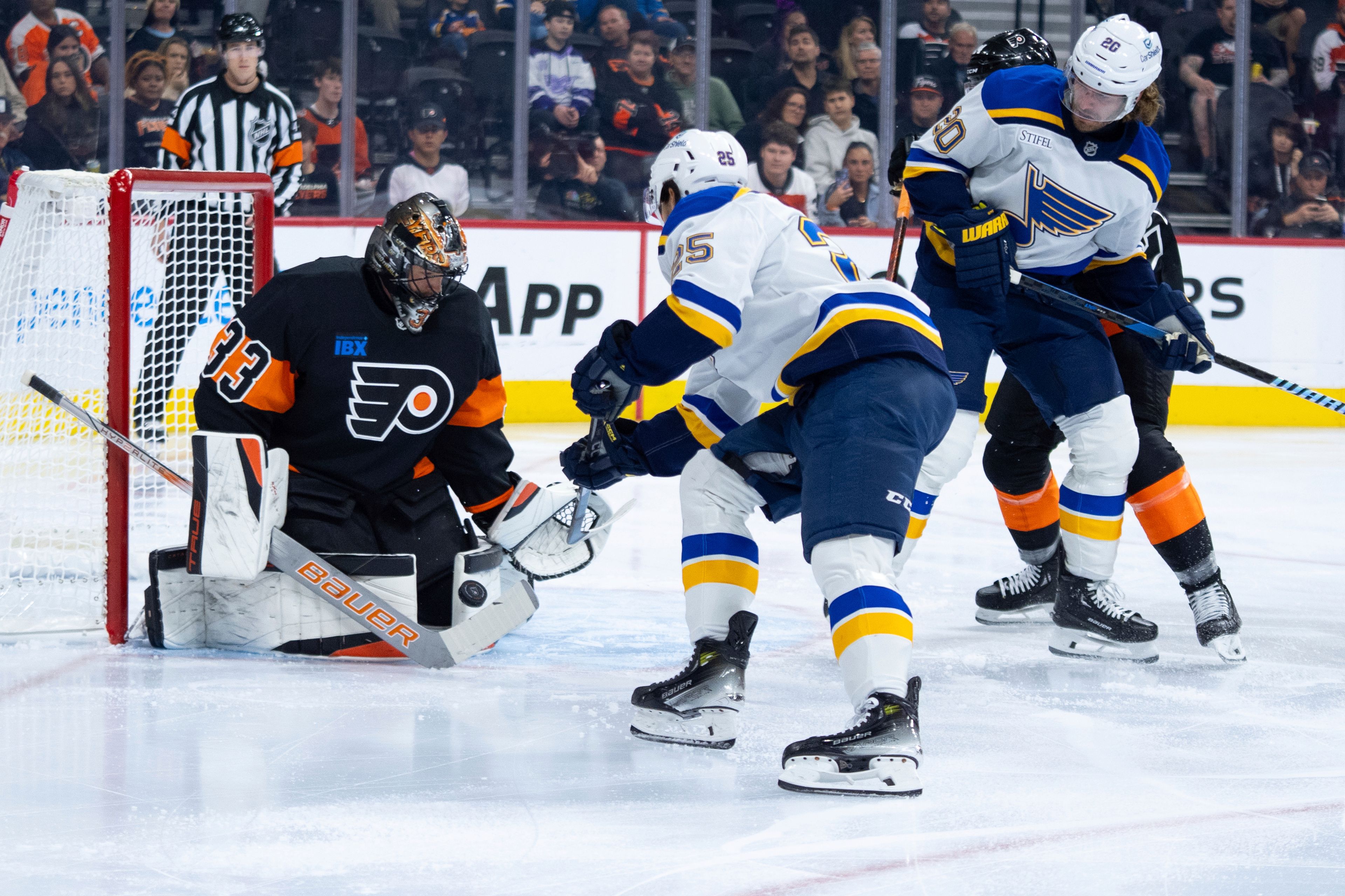 Philadelphia Flyers' Samuel Ersson, left, makes the save on the shot by St Louis Blues' Jordan Kyrou, center, during the first period of an NHL hockey game, Thursday, Oct. 31, 2024, in Philadelphia. (AP Photo/Chris Szagola)