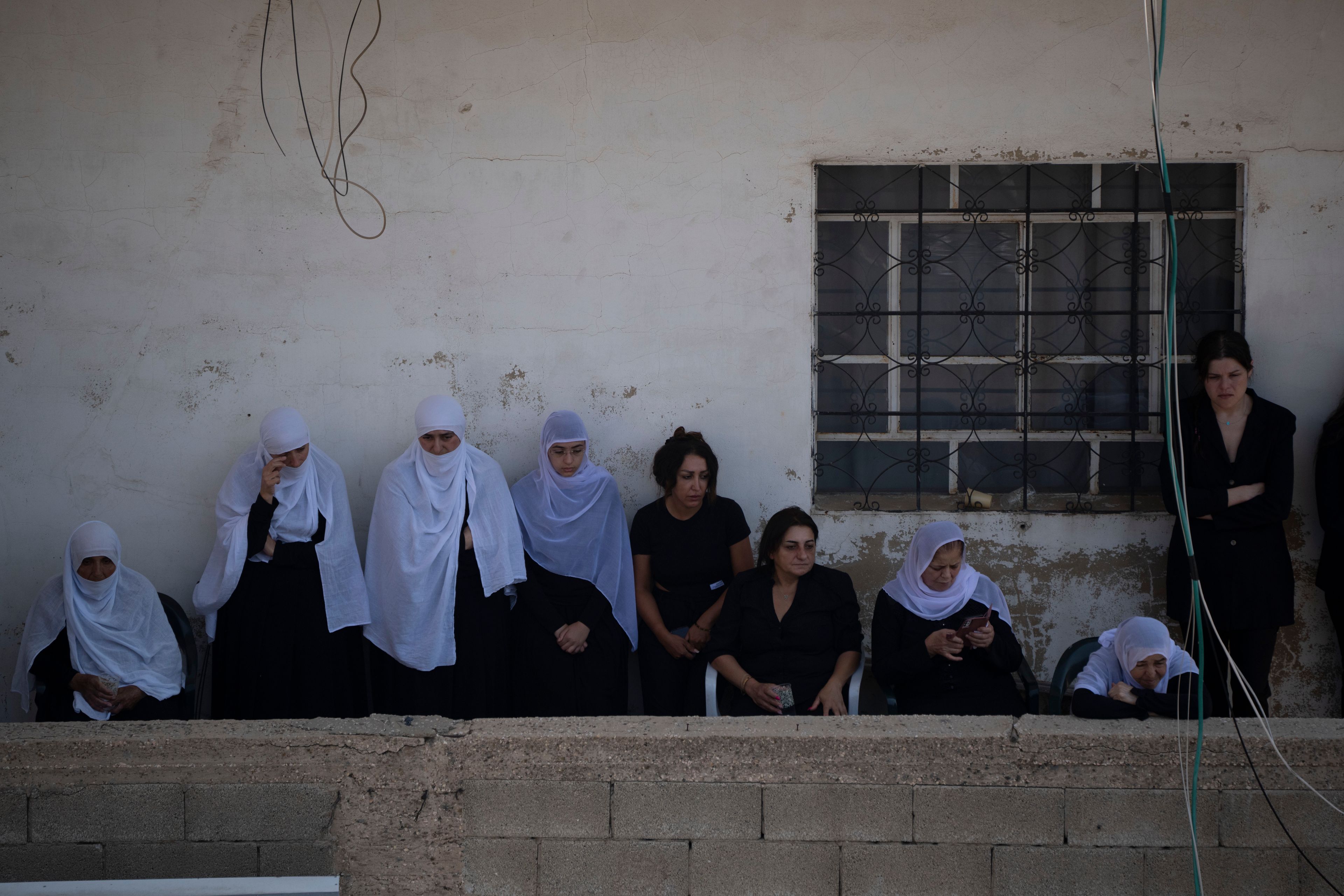 Mourners from the Druze minority watch from a balcony the funeral of some of the 12 children and teens killed in a rocket strike at a soccer field in the village of Majdal Shams, in the Israeli-annexed Golan Heights, Sunday, July 28, 2024. It's the deadliest strike on an Israeli target along the country's northern border since the fighting between Israel and the Lebanese militant group Hezbollah began. (AP Photo/Leo Correa)