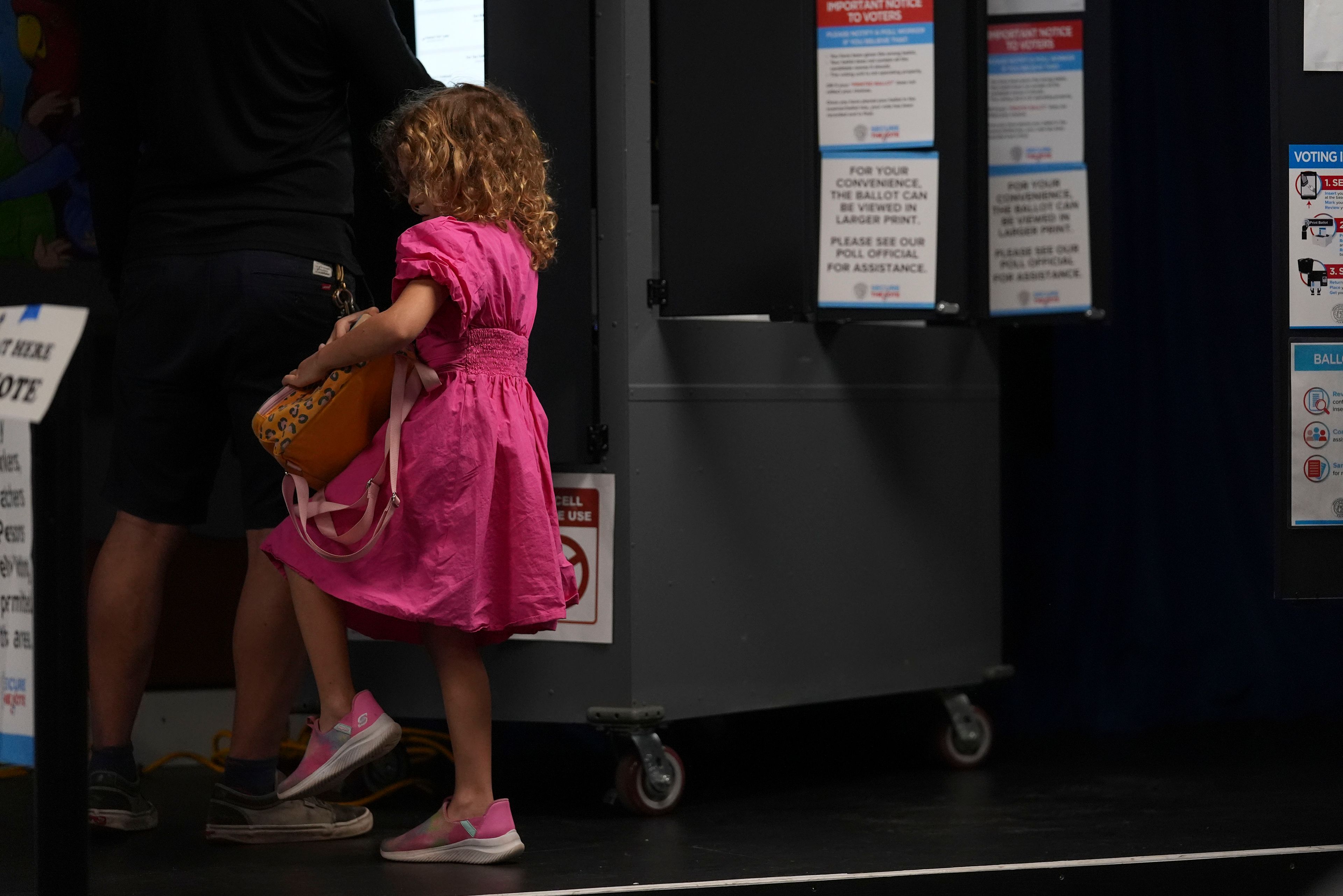 A young girl accompanies her father as he votes at a polling place inside Dad's Garage Theatre Company, Tuesday, Nov. 5, 2024, in Atlanta. (AP Photo/Brynn Anderson)