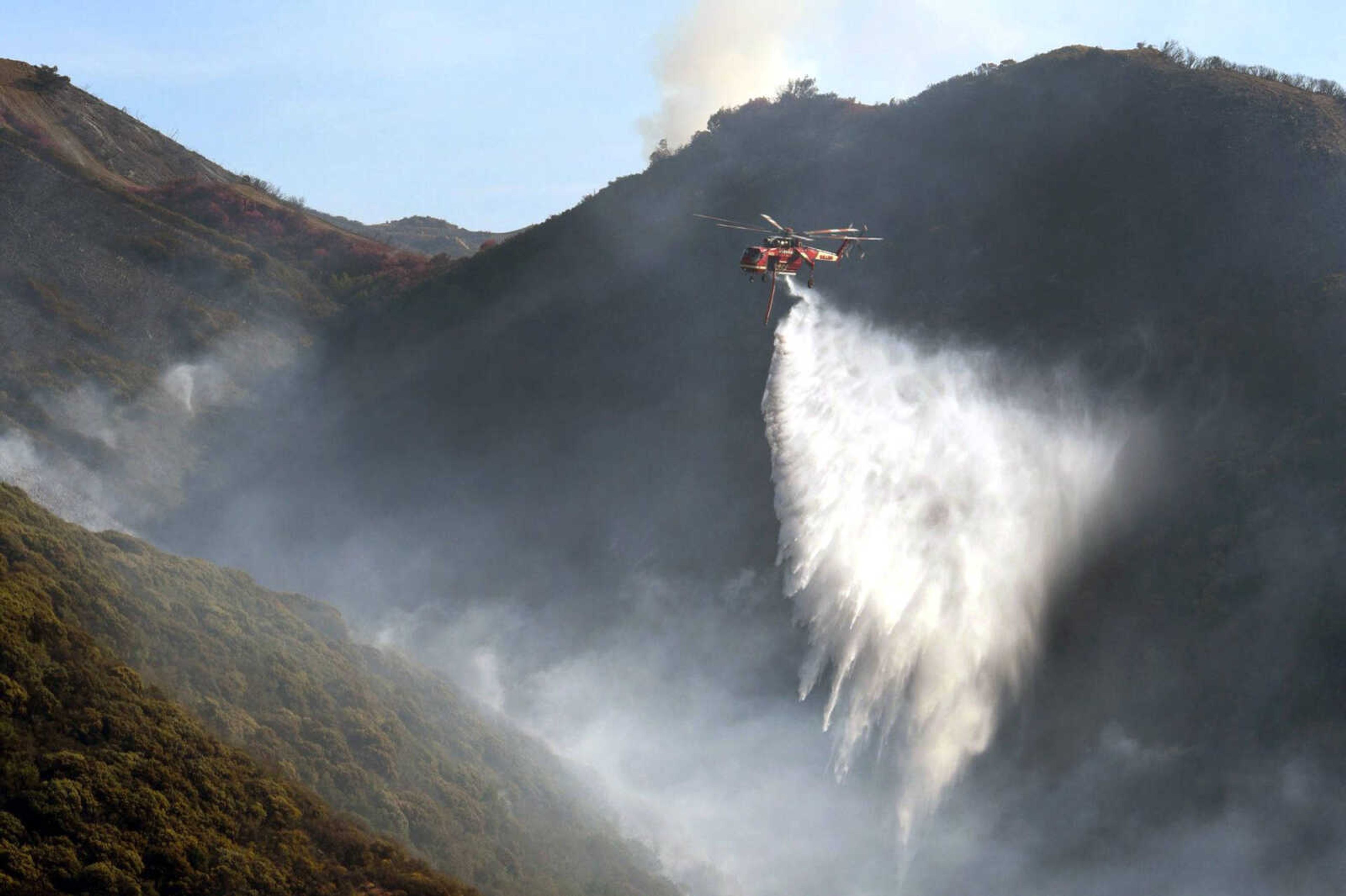 A Sikorsky S-64 Skycrane makes a water drop on hot spots along the hillside east of Gibraltar Road on Sunday morning in Santa Barbara, California.