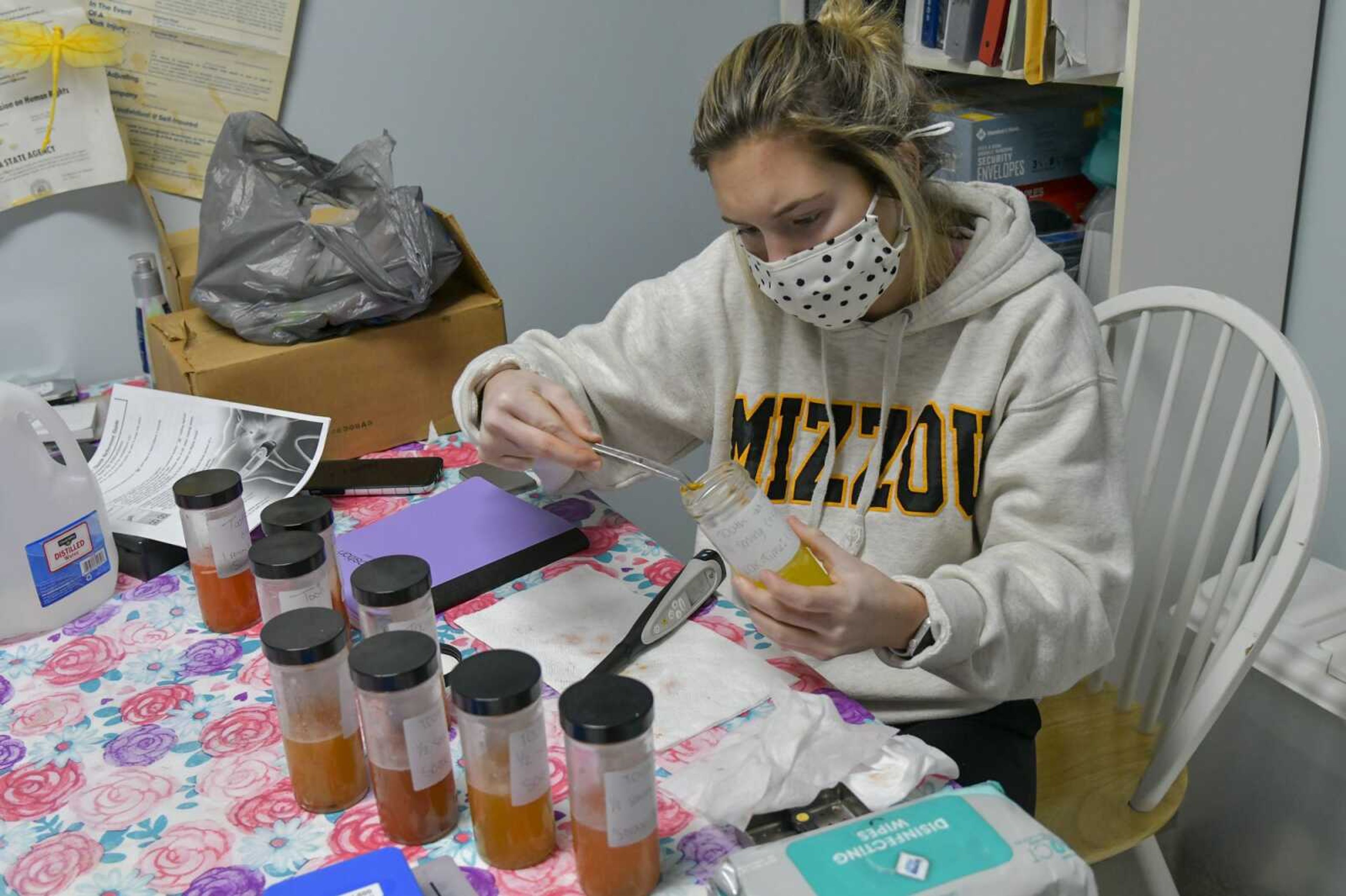 Junior Reagan Newell removes a tooth from her skittle solution so she can record the amount of enamel it has after it soaked in the solution in the break room of Cotner Dental in Cape Girardeau on Dec. 15, 2020.