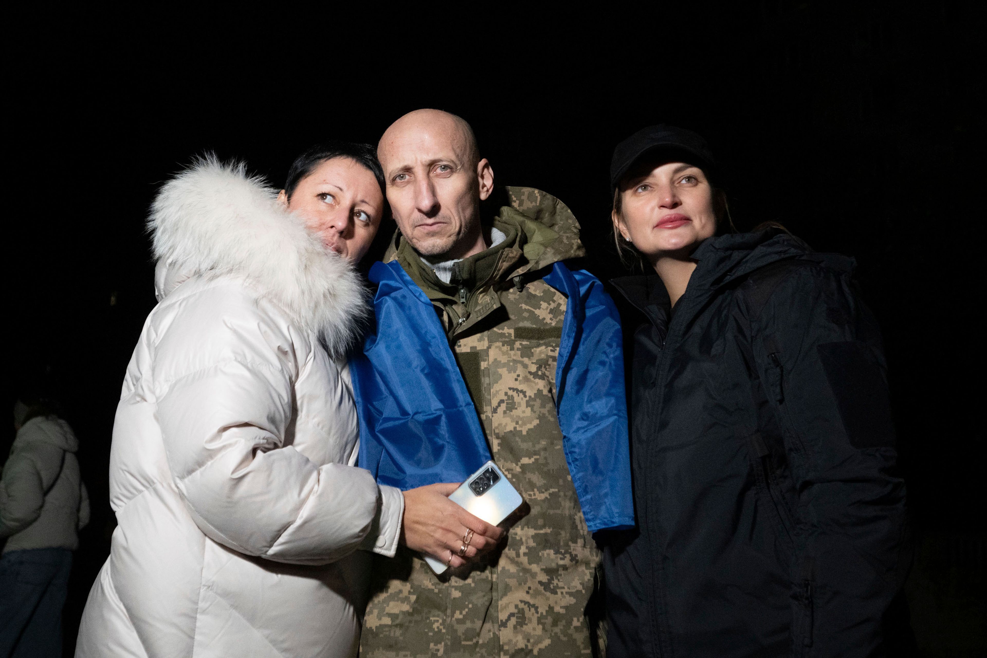 In this photo provided by the Press Service of the President of Ukraine on Oct. 19, 2024, a Ukrainian serviceman hugs his relatives after returning from captivity during a POWs exchange in an undisclosed location, Ukraine. (Press Service of the President of Ukraine via AP)