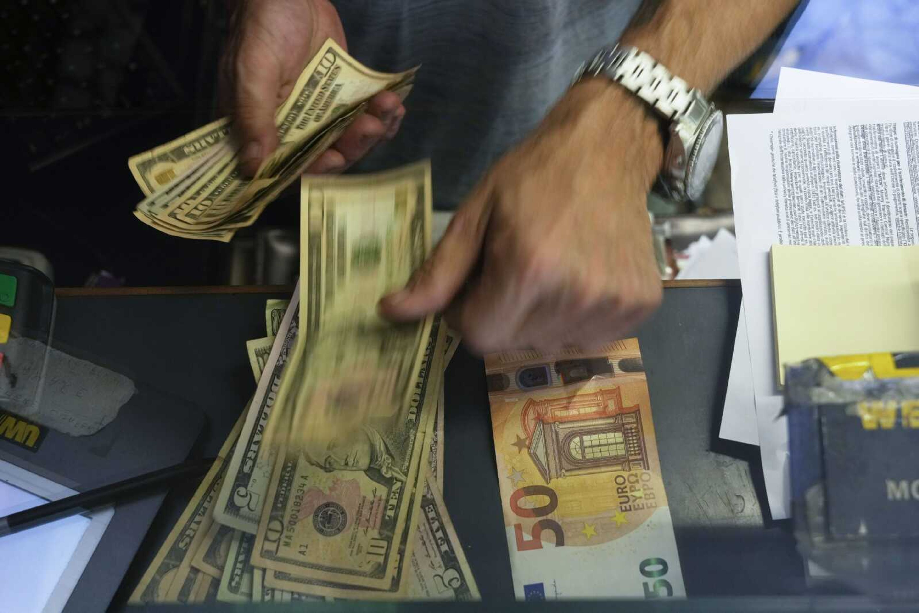 A cashier changes a 50 euro banknote with U.S. dollars at an exchange counter Wednesday in Rome. The euro on Tuesday fell to parity with the dollar for the first time in nearly 20 years.