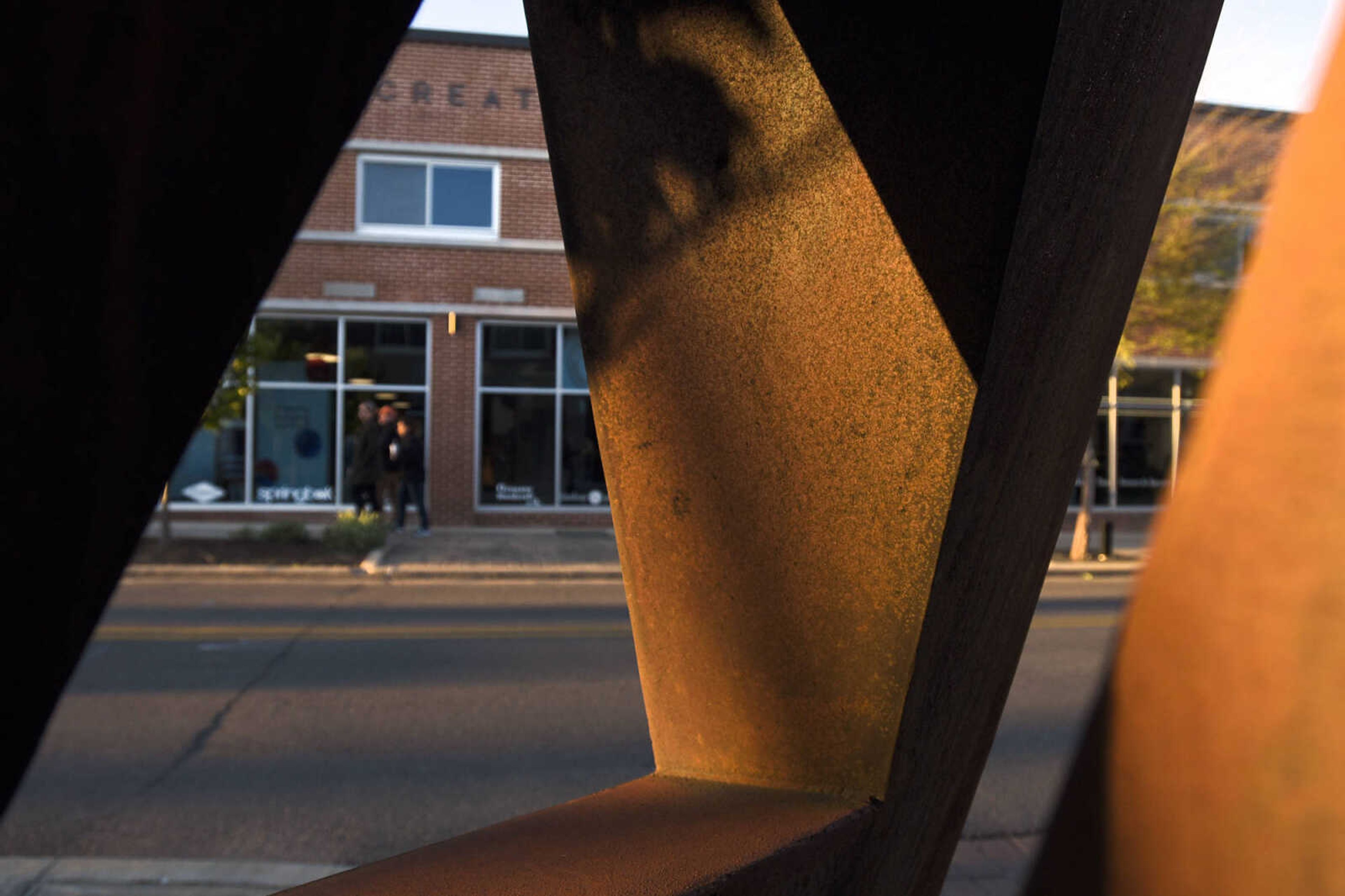 People walk along Broadway across from Carl Billingsley's sculpture, "Eyes of Dawn" on Thursday evening, April 6, 2017, in Cape Girardeau.