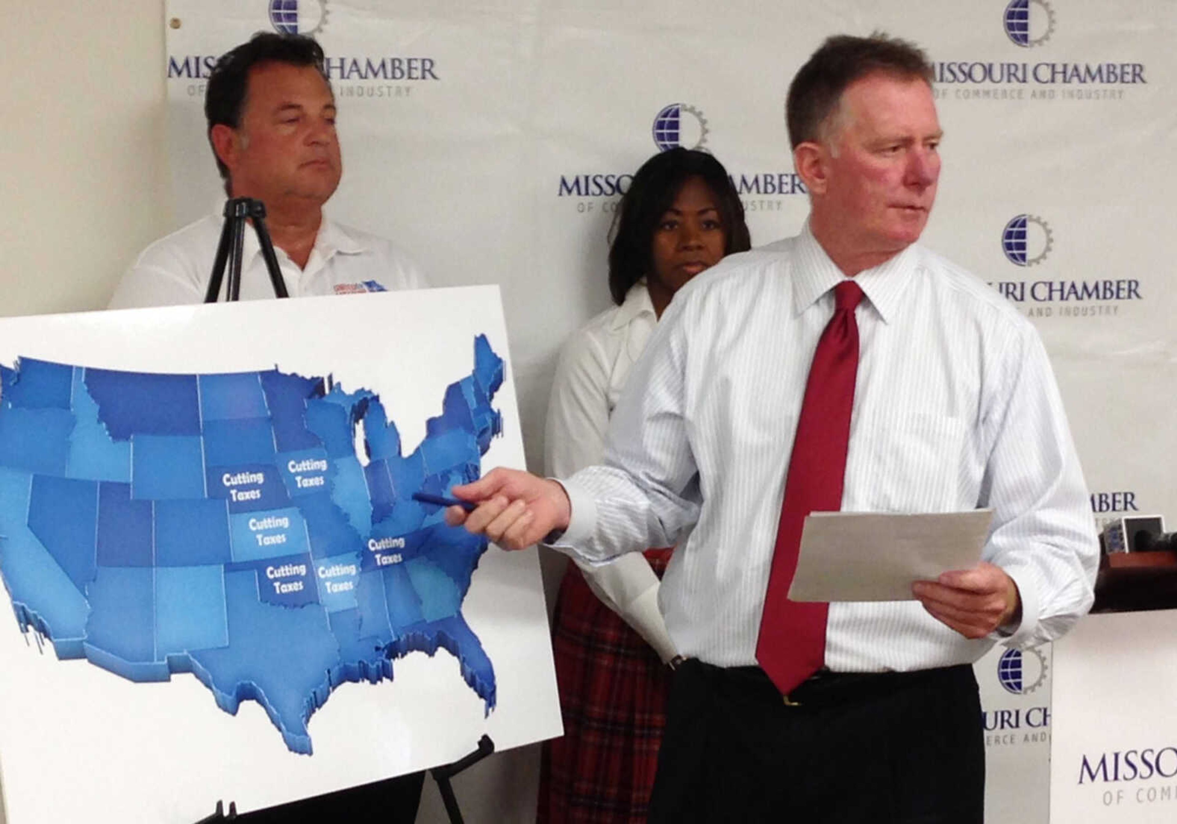 Dan Mehan, right, president and CEO of the Missouri Chamber of Commerce and Industry, points to a map of states surrounding Missouri that have recently cut taxes during a news conference Friday, Aug. 23, 2013, in Jefferson City, Mo. Mehan wants legislators to override Gov. Jay Nixon's veto of a tax-cut bill. United for Missouri Executive Director Carl Bearden, left, and Missouri Club for Growth Chairwoman Bev Randles joined Mehan in saying that the tax-cut vote would be important in determining whom their groups support in the 2014 elections. (AP Photo/David Lieb)