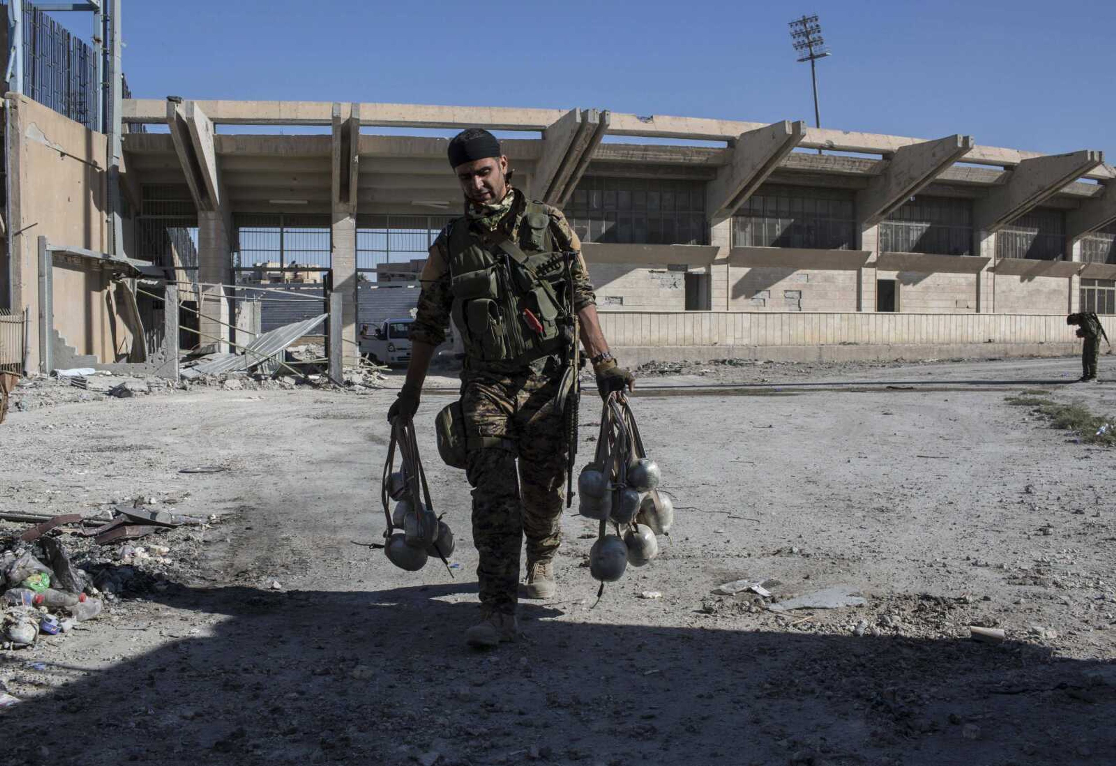 A member of U.S.-backed Syrian Democratic Forces carries explosives Wednesday at a stadium that was the site of Islamic State fighters' last stand in the city of Raqqa, Syria.