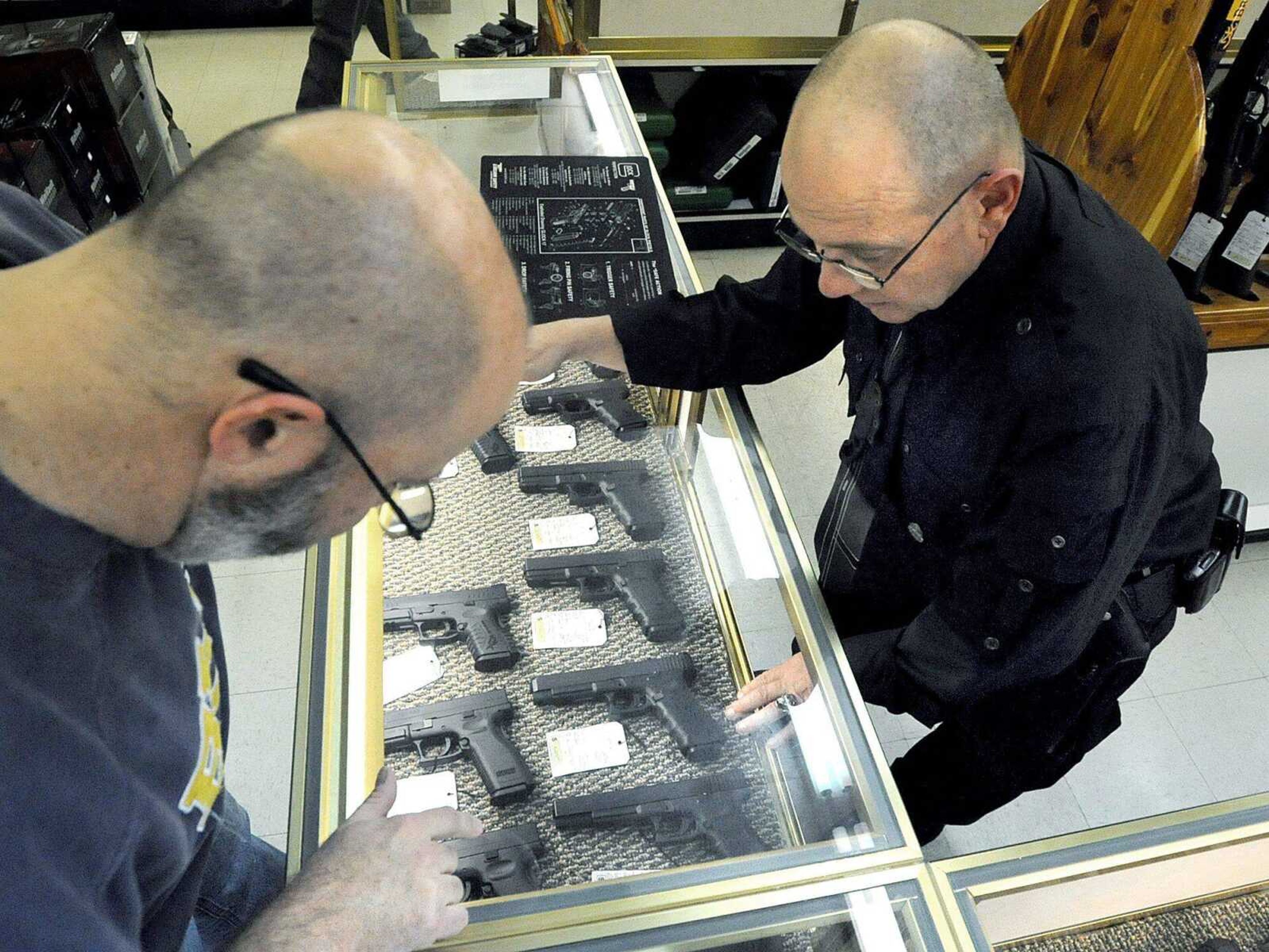 Shooters Gun Shop sales associate Gene Colyer assists Jeff Schott as he looks over a Springfield SD 45 Automatic Colt Pistol Wednesday afternoon, Dec. 19, 2012 in Cape Girardeau. (Laura Simon)