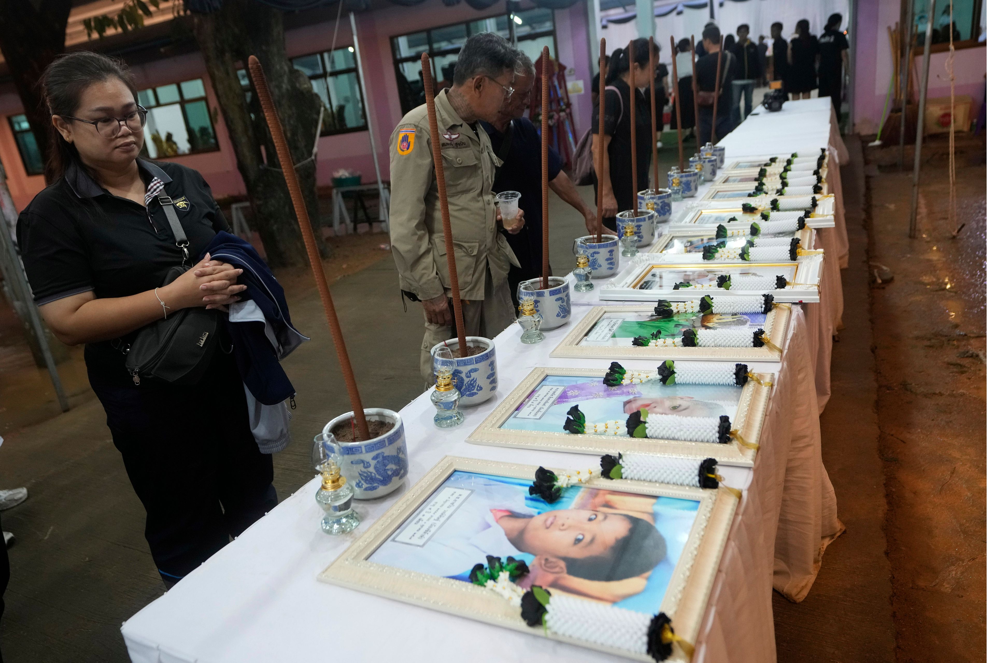 Relatives of the bus fire victims view their portraits at the Wat Khao Phraya Sangkharam School Lan Sak, Uthai Thani province, Thailand, Wednesday, Oct. 2, 2024. (AP Photo/Sakchai Lalit)