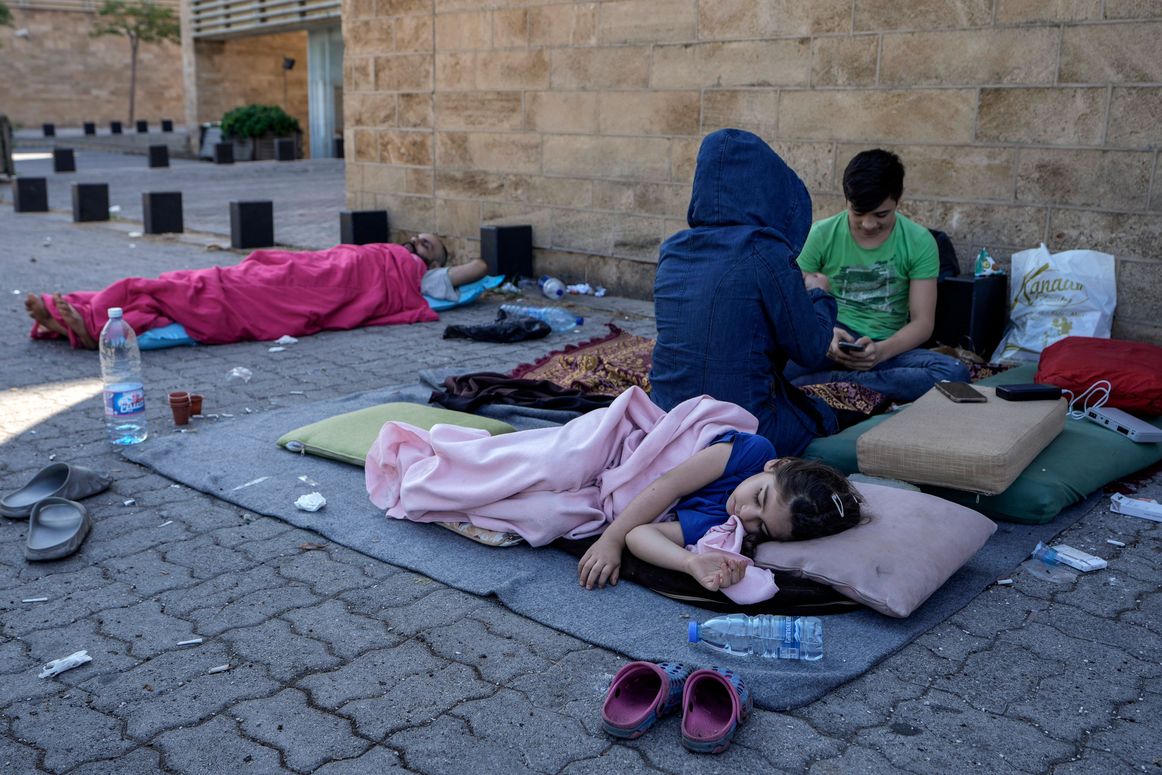 A family sleep on the ground in Beirut's corniche area after fleeing the Israeli airstrikes in the southern suburbs of Dahiyeh, Sunday, Sept. 29, 2024. (AP Photo/Bilal Hussein)