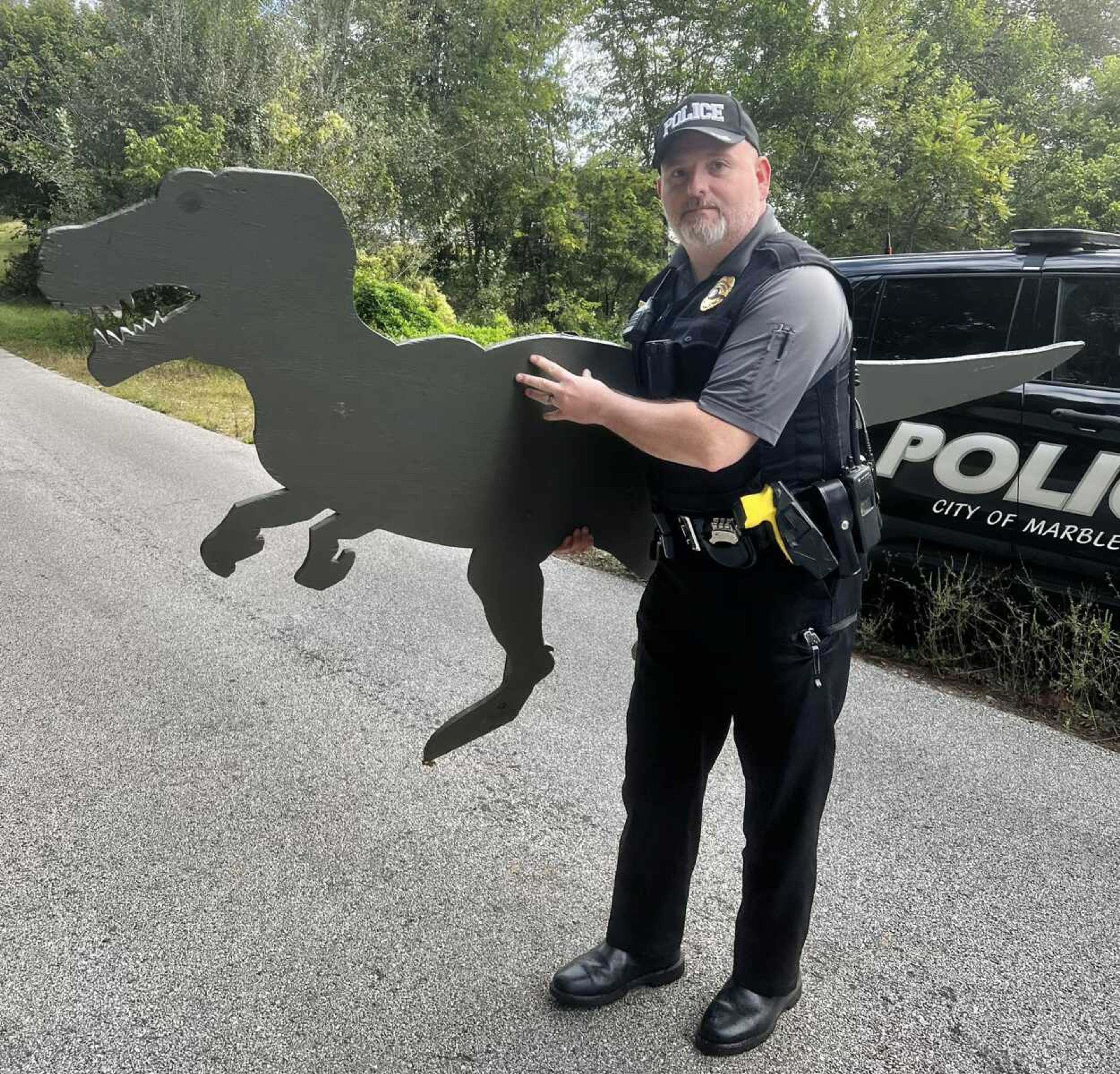 Marble Hill Police Department Capt. Jerry Gilliam hauls a missing dinosaur decoration Oct. 3 after discovering it on the porch of an abandoned house. The dinosaur was taken from the premises of a bank by a teenage prankster, but recovered in time for a weekend fall festival.