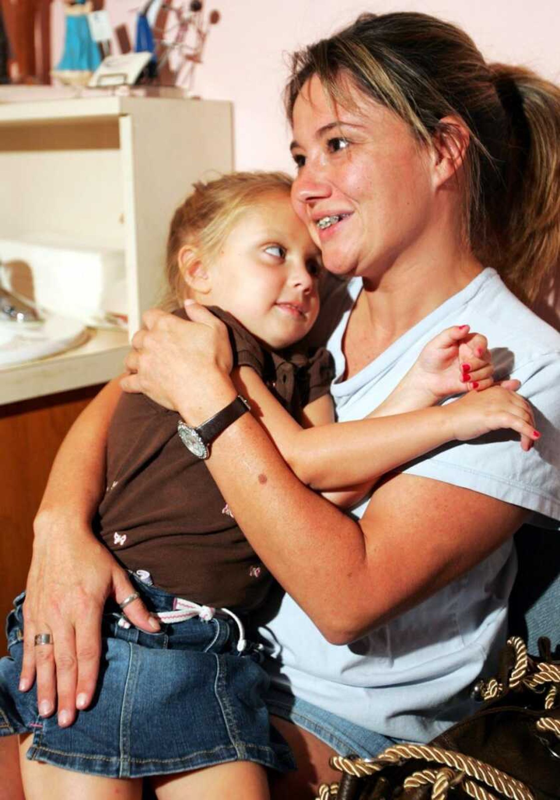 Dawn Barlett of Webb City, Mo., held her daughter, Rylea, who will be 6 on Monday, at the Brothers optometrist office Aug. 30 in Joplin, Mo. Rylea Barlett has been seeing Dr. Larry Brothers about her newfound eyesight. Rylea was blind when her mother took her to Asia in July for a stem cell injection. Her eyesight has been developing since then. (T. Rob Brown ~ The Joplin Globe)