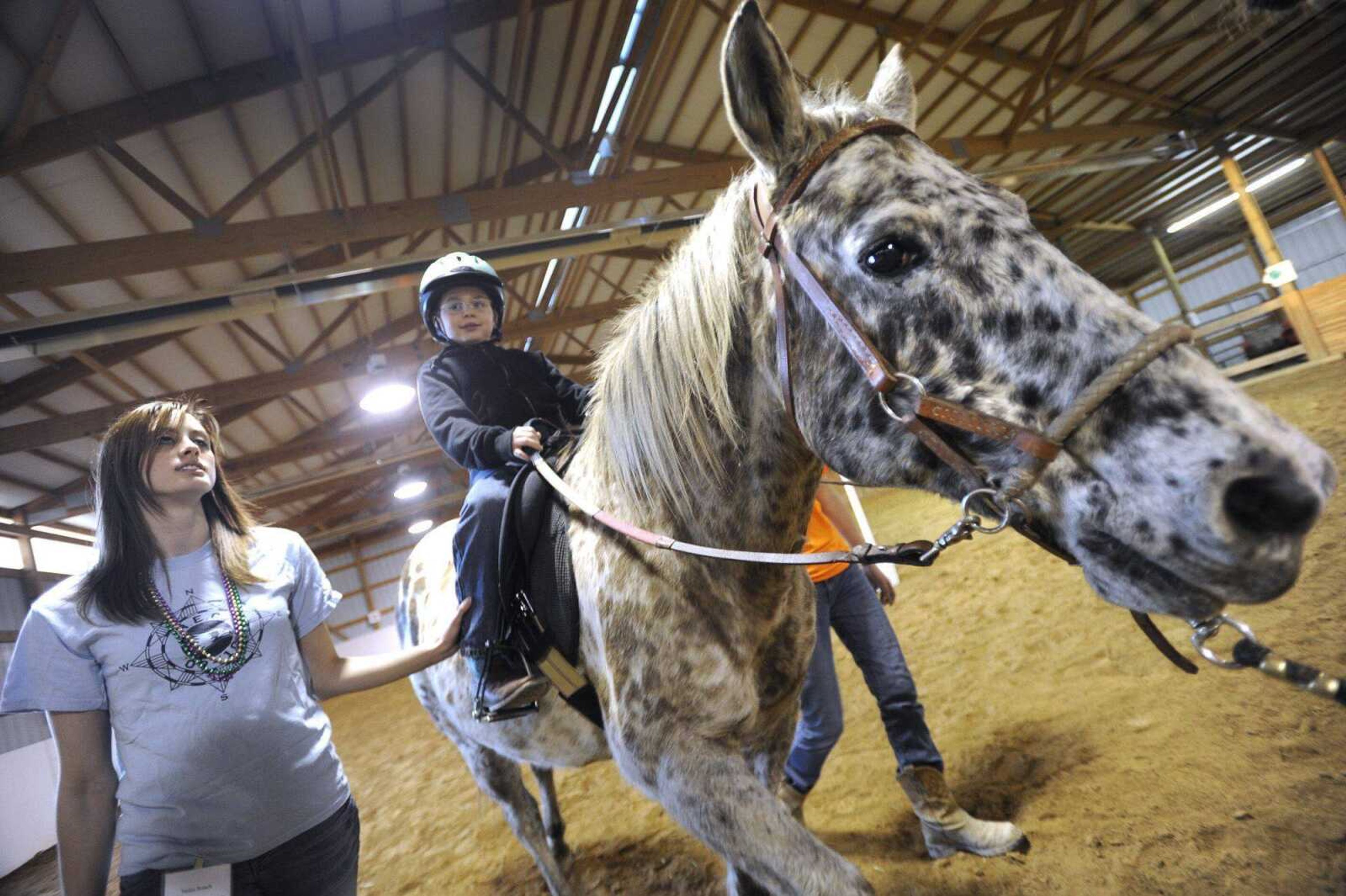 Michael Foltz takes a ride on Siri, with assistant Helen Roach during a lesson Feb. 23 with Mississippi Valley Therapeutic Horsemanship. (Fred Lynch)