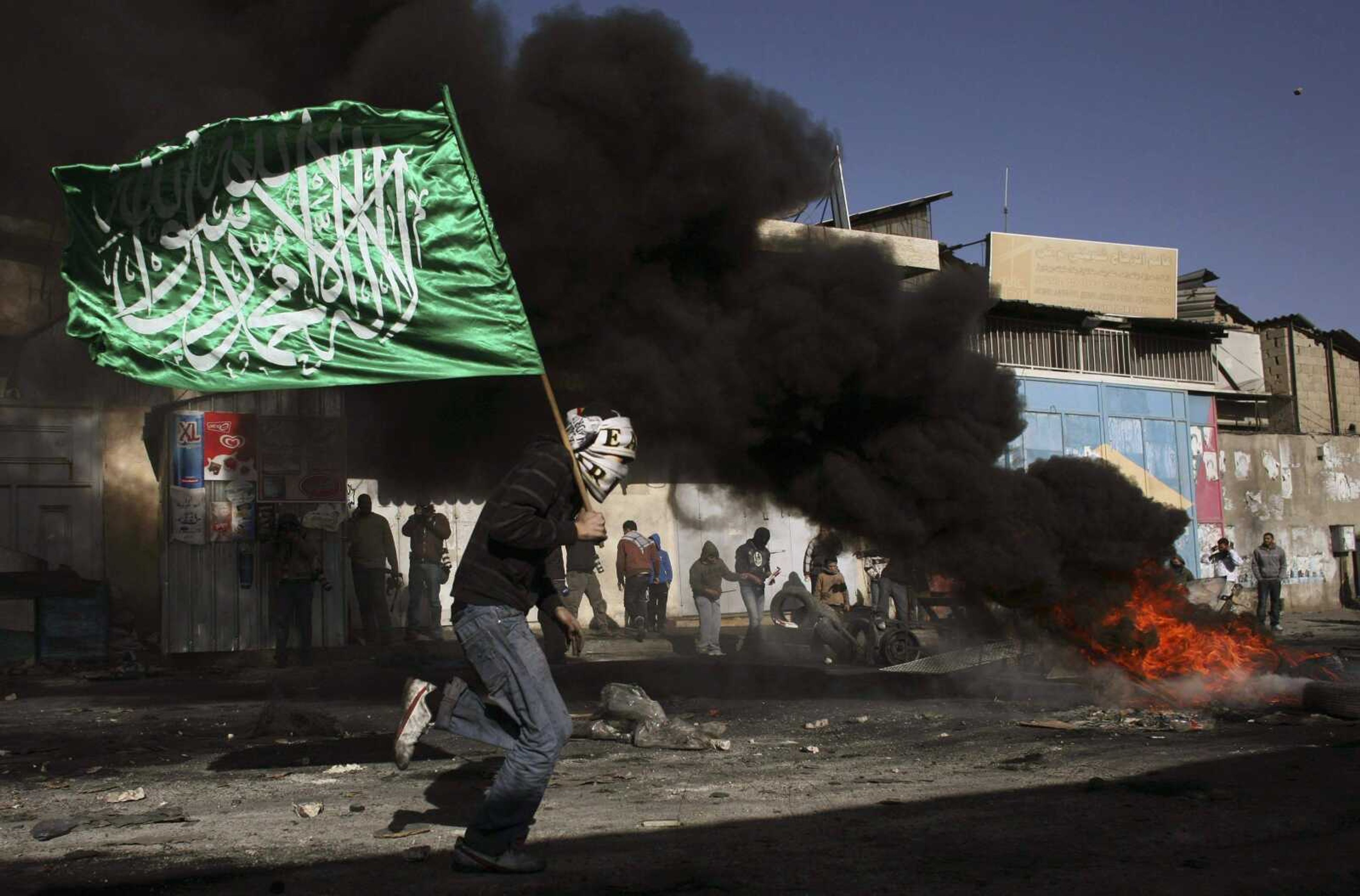 A Palestinian protester runs with a green Islamic flag during clashes with Israeli troops, not seen, at a demonstration against Israel's military operation in Gaza, in the Shuafat refugee camp, on the outskirts of Jerusalem, Sunday, Dec. 28, 2008. More than 280 Palestinians have been killed and more than 600 people wounded since Israel's campaign to quash rocket barrages from Gaza began midday Saturday. (AP Photo/Dan Balilty)