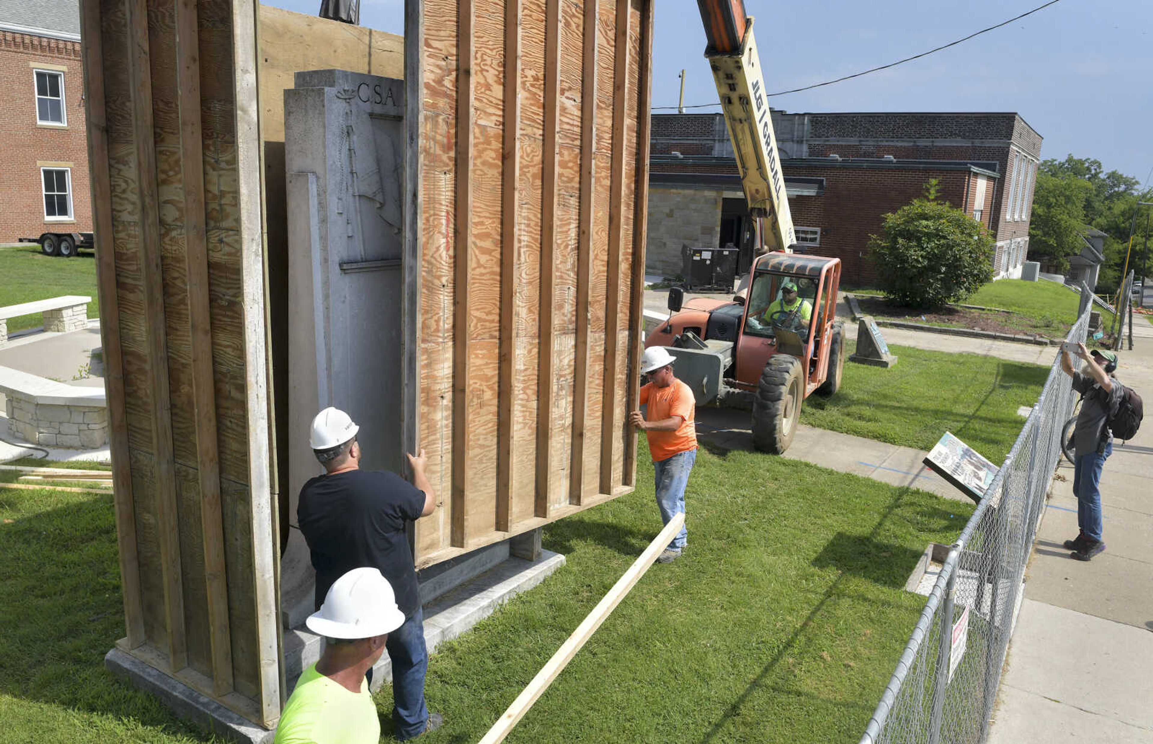 David Langely, right, records video footage of construction workers erecting a wooden box around a Confederate States of America monument in Ivers Square on Tuesday, July 7, 2020, in Cape Girardeau.