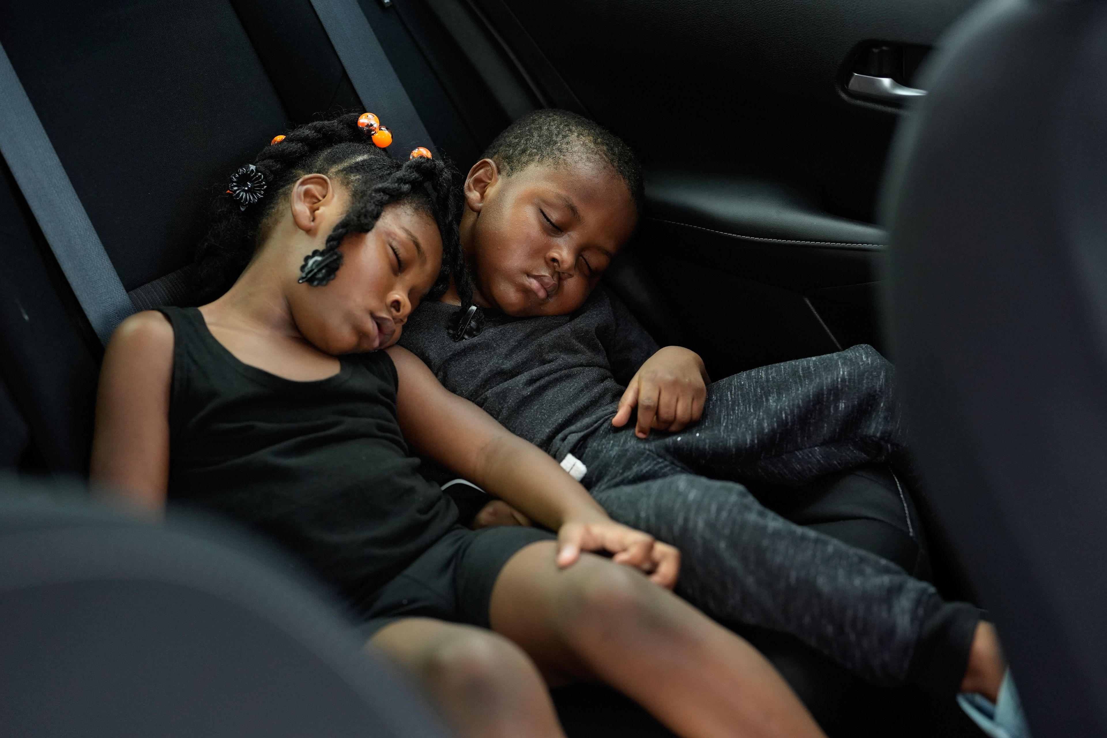 Siblings Saboria, 4, left, and Messiah Tyler, 3, nap in the backseat of a car after the roof was torn off the home where they lived with their mom, grandparents, an aunt and an uncle during the passage of Hurricane Milton, in Palmetto, Fla., Thursday, Oct. 10, 2024. The family of 7 rode out the storm in a government shelter, and returned home to find most of the roof gone and their furniture and belongings destroyed by rainwater. (AP Photo/Rebecca Blackwell)