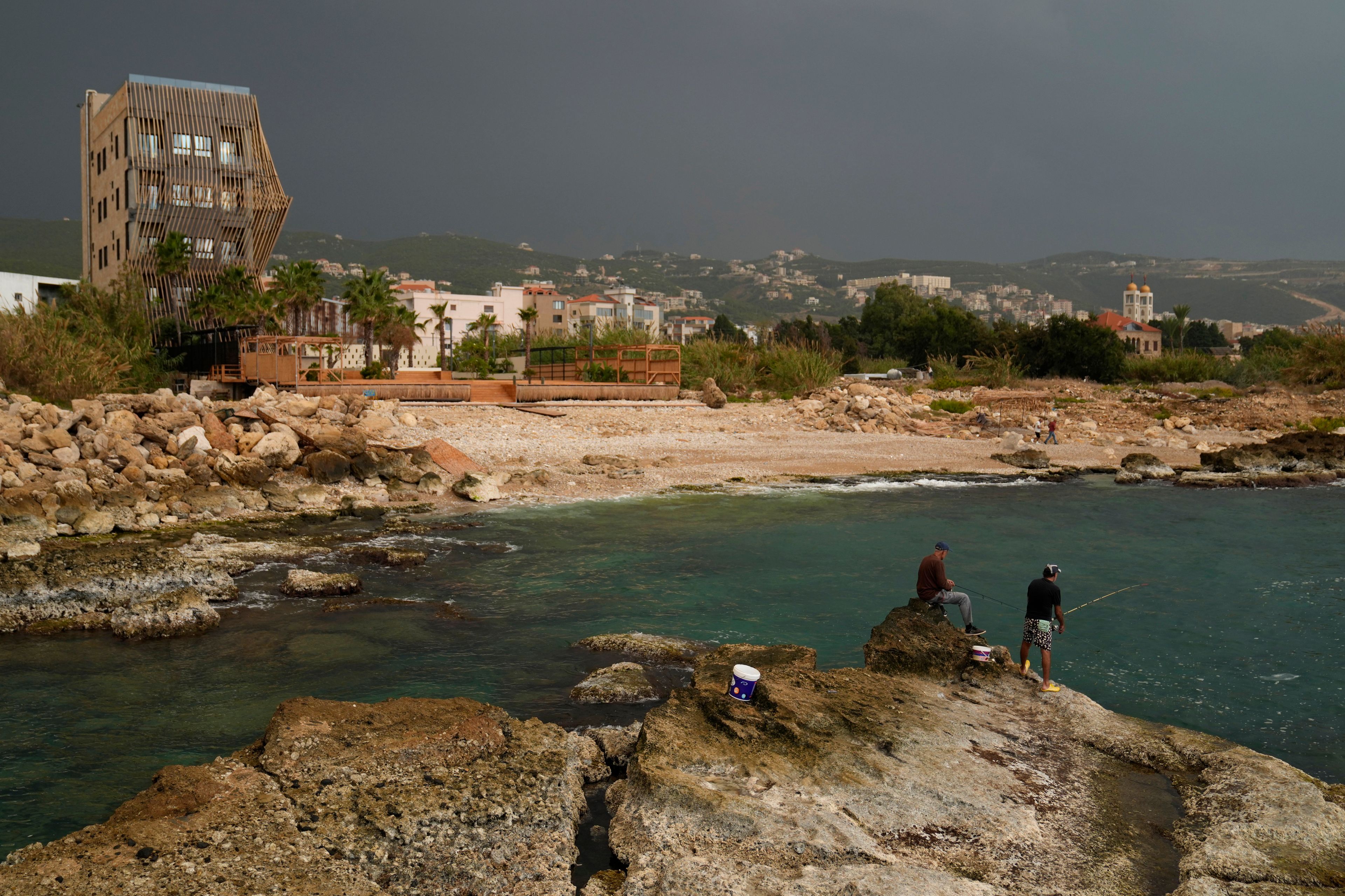 Lebanese fishermen cast their fishing rods at a beach in Batroun, northern Lebanon, Saturday, Nov. 2, 2024, where Lebanese officials say a ship captain was taken away by a group of armed men who landed on a coast north of Beirut and they're investigating whether Israel was involved. (AP Photo/Hussein Malla)