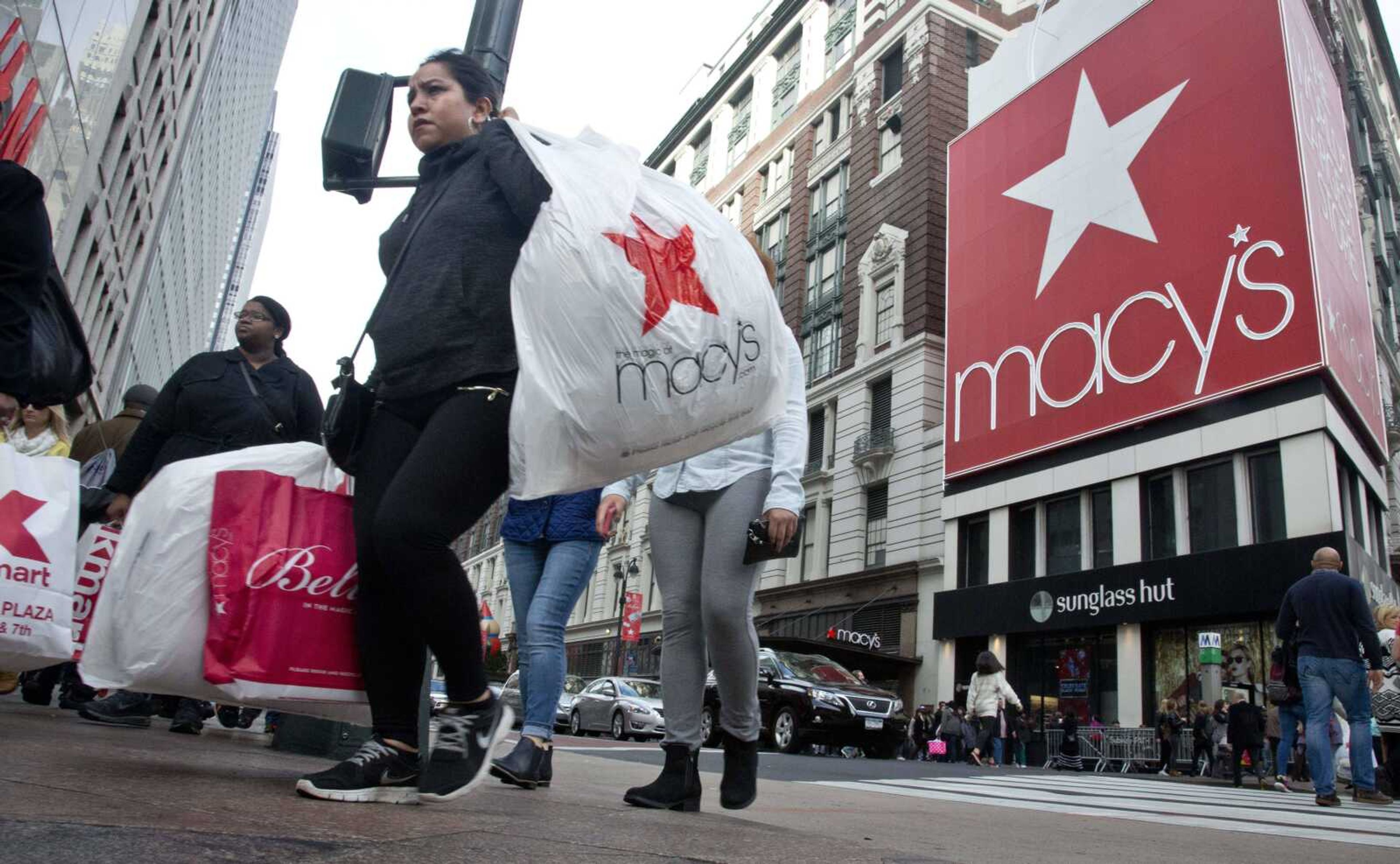 Shoppers carry bags Nov. 27 as they cross a pedestrian walkway near Macy's in Herald Square in New York. Unseasonably warm weather across much of the country has left some people feeling cold about holiday shopping. (Bebeto Matthews ~ Associated Press)