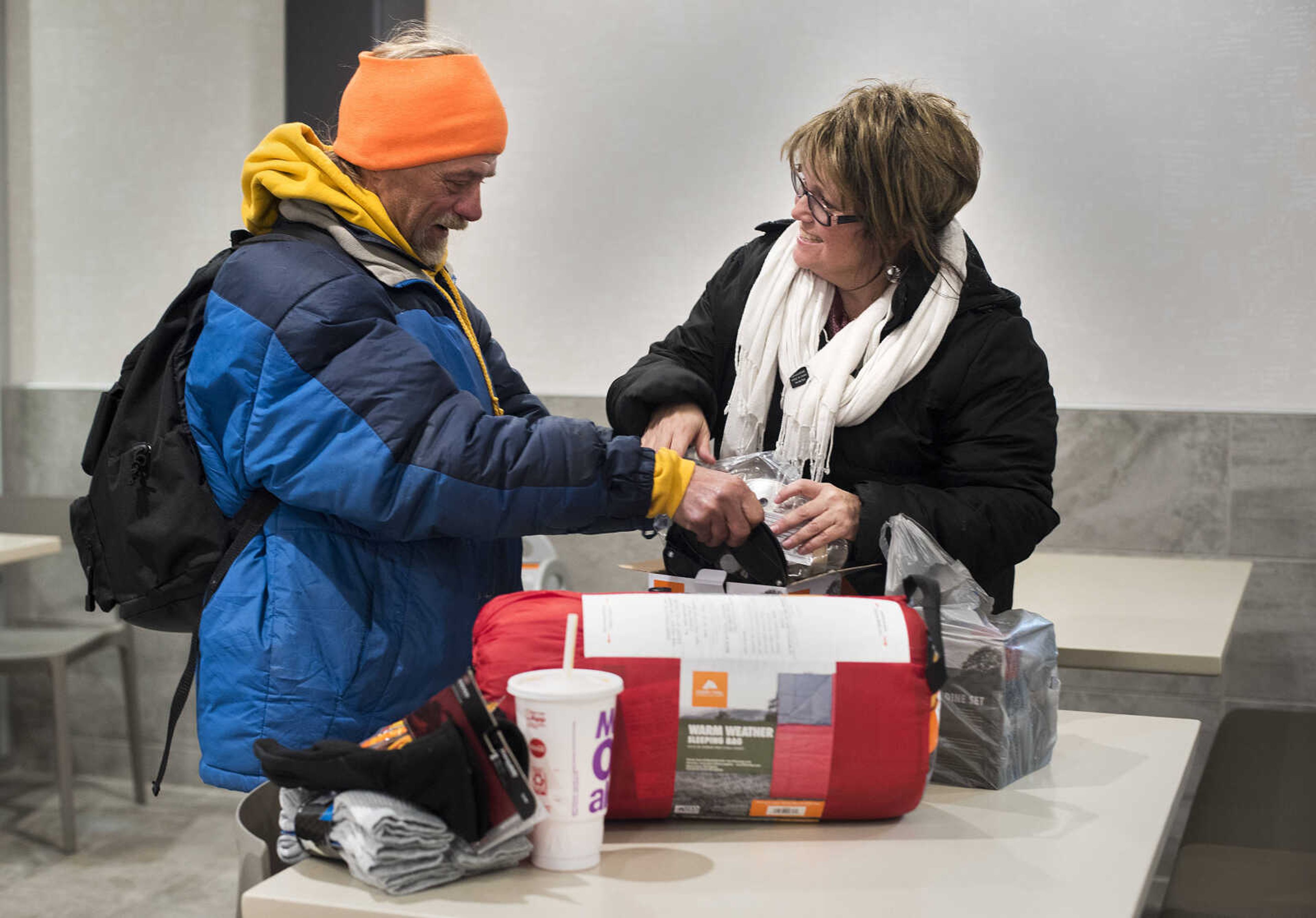 Rev. Renita Green, pastor of St. James AME Church, delivers camping supplies and hand warmers to Paul York, left, as snow begins to fall Wednesday evening, Nov. 14, 2018, in Cape Girardeau.