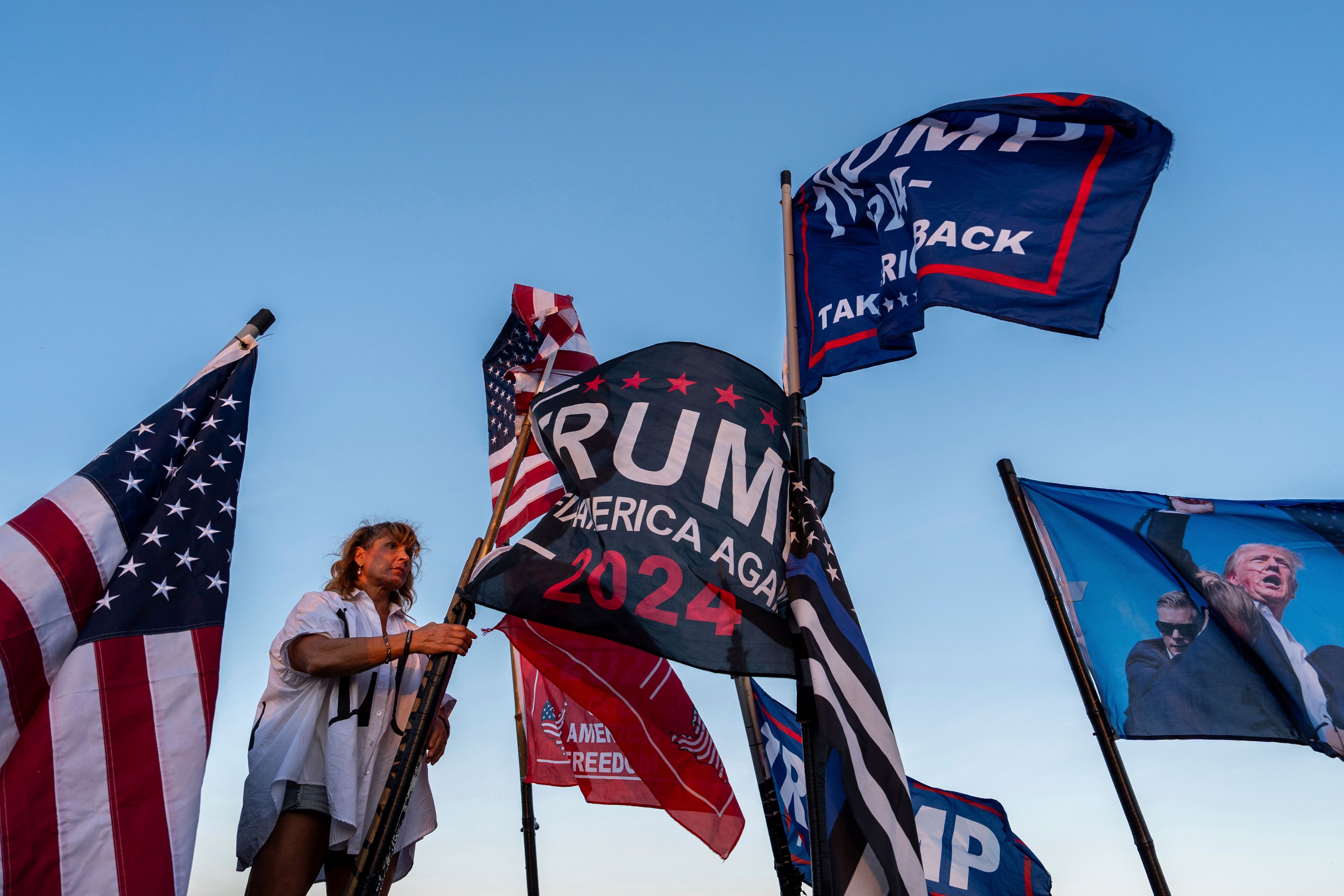 Nikki Fuller, 56, sets up flags on her truck near the Mar-a-Lago estate of President-elect Donald Trump, Monday, Nov. 11, 2024, in Palm Beach, Fla. (AP Photo/Julia Demaree Nikhinson)