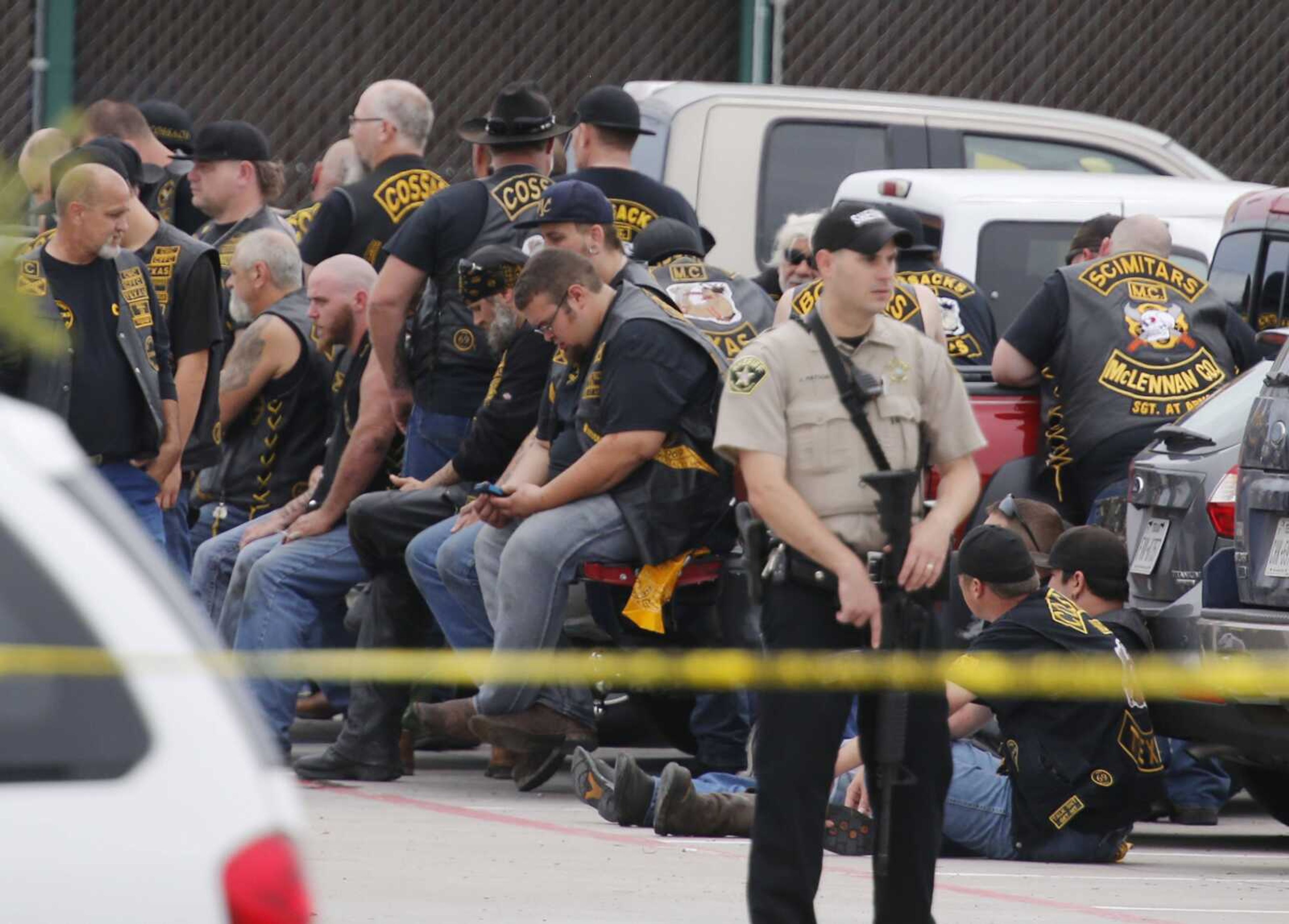 A McLennan County deputy stands guard near a group of bikers in the parking lot of a Twin Peaks restaurant Sunday in Waco, Texas. (Rod Aydelotte ~ Waco Tribune-Herald)