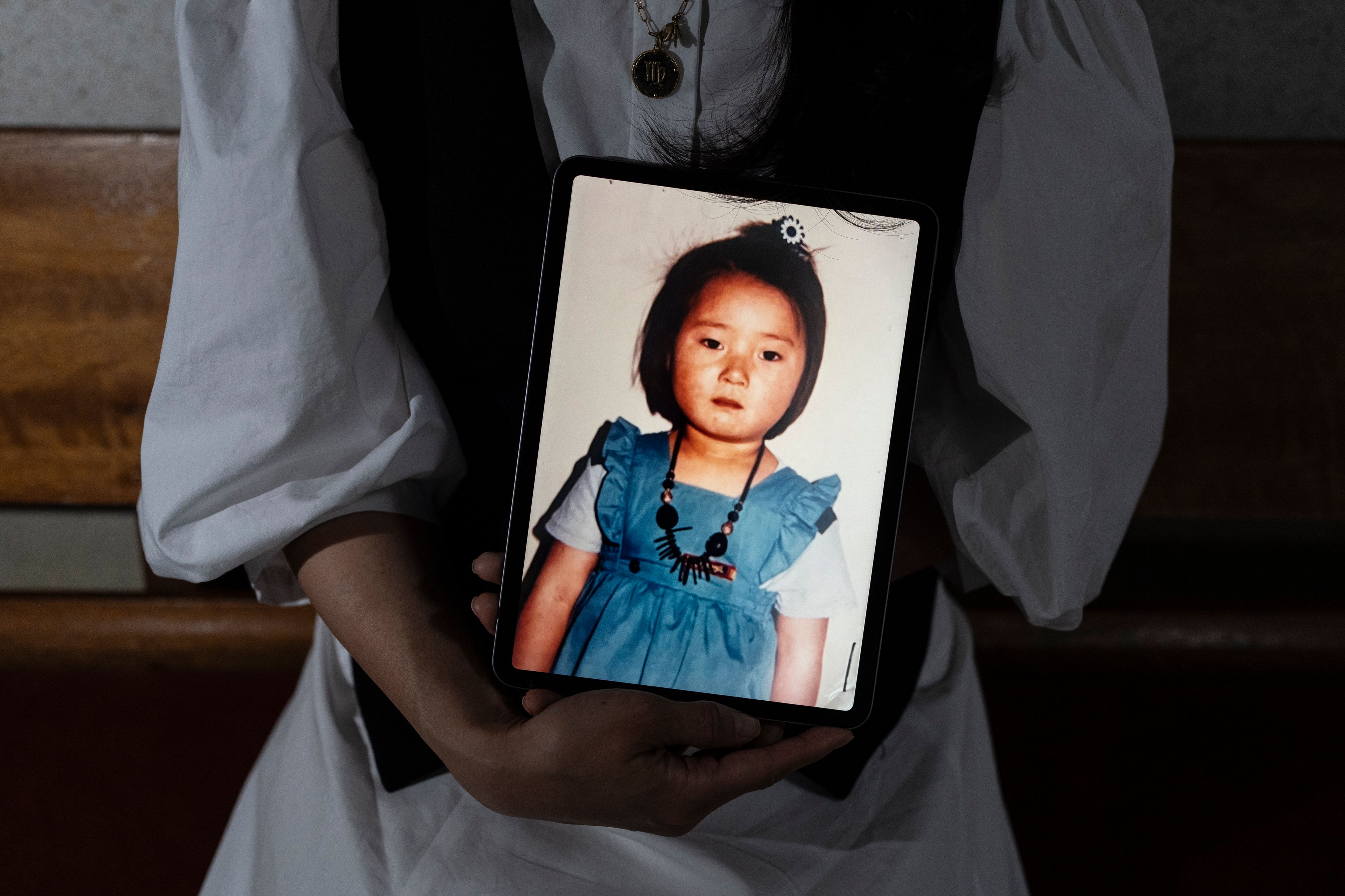 Nicole Motta, an adoptee visiting from Los Angeles, holds a tablet displaying a childhood picture, while traveling to search for her birth family in Yongin, South Korea, Thursday, May 30, 2024. Motta, whose Korean name is Jang Hyeon-jung, visited the site that used to be the orphanage where she stayed until her adoption. (AP Photo/Jae C. Hong)