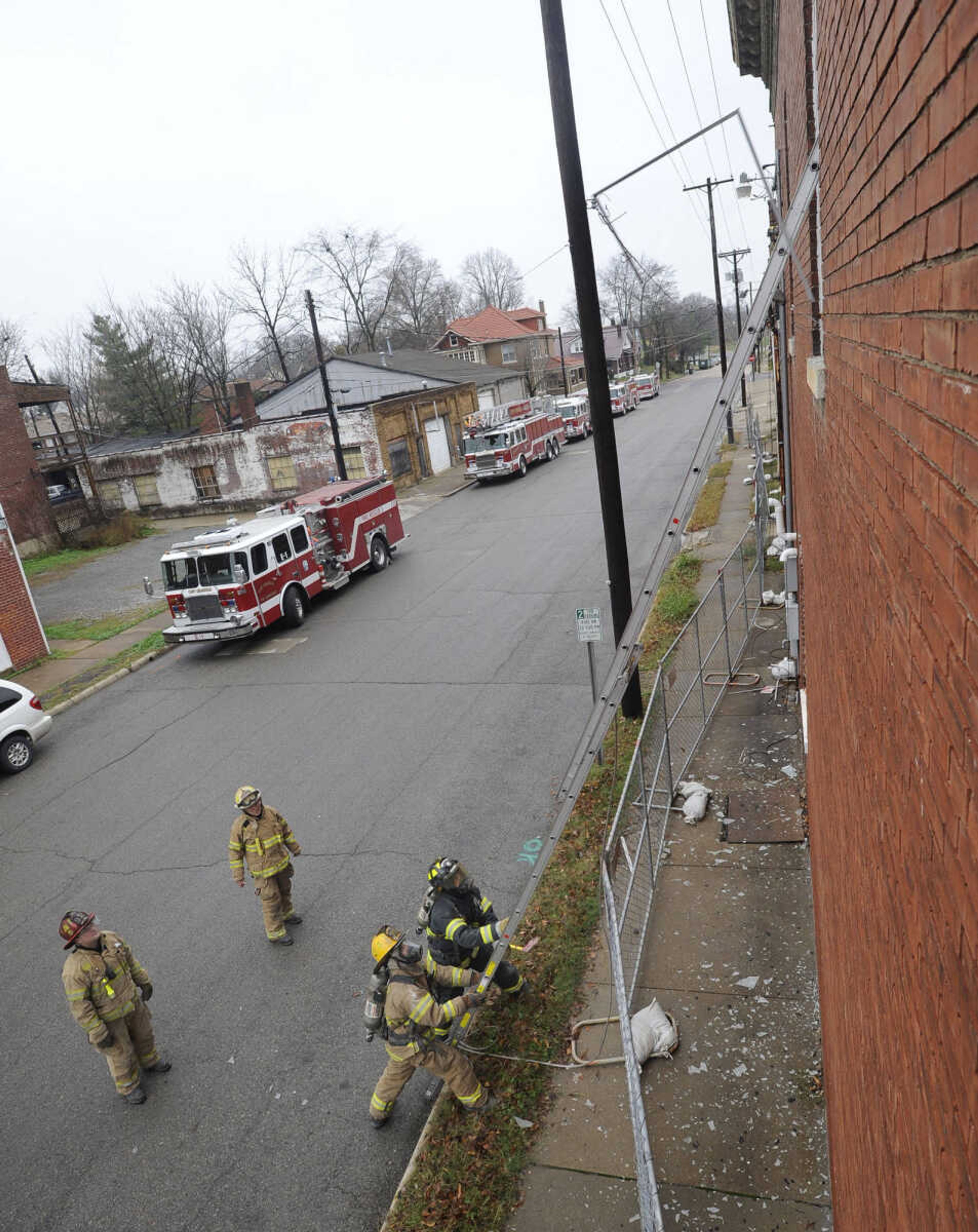 Battalion Chief Fred Vincel directs firefighters in breaking a window by using the ladder before climbing it to clear the window frame.