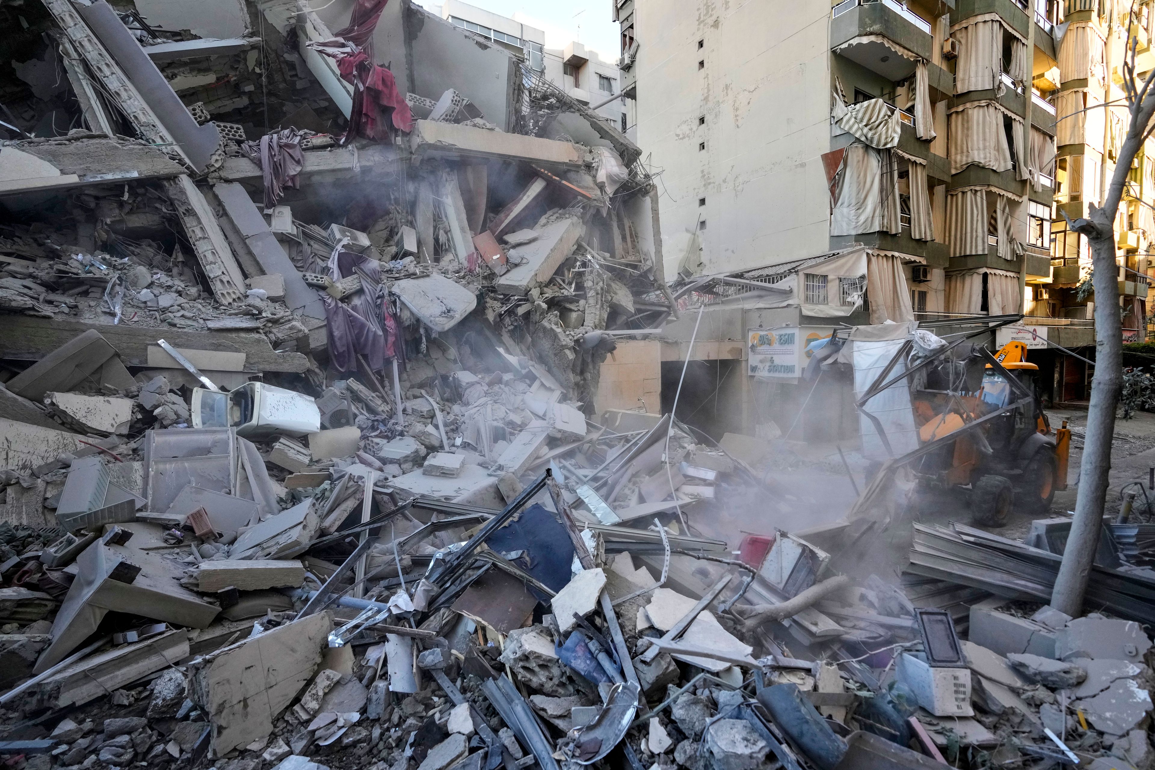 Rescue workers use a bulldozer to remove rubble of destroyed buildings at the site of an Israeli airstrike on Sunday night that hit several branches of the Hezbollah-run al-Qard al-Hassan in Beirut's southern suburb, Lebanon, Monday, Oct. 21, 2024. (AP Photo/Hassan Ammar)