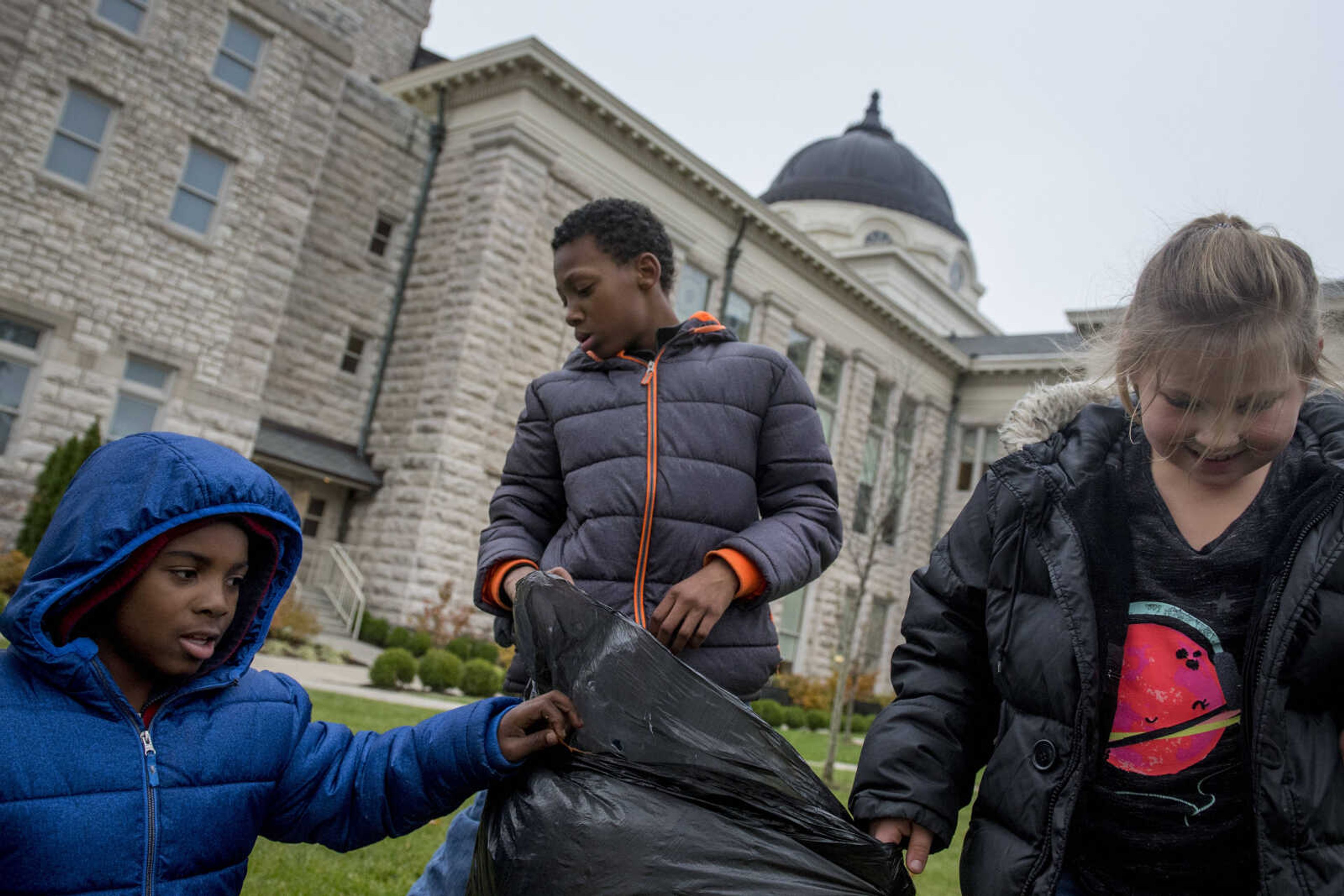 Jefferson Elementary students, from left, Lamonquez Vaughn, Kevin Miles and Loretta Hogan fill a garbage bag with debris on the Southeast Missouri State University campus as part of a beautification project Monday.