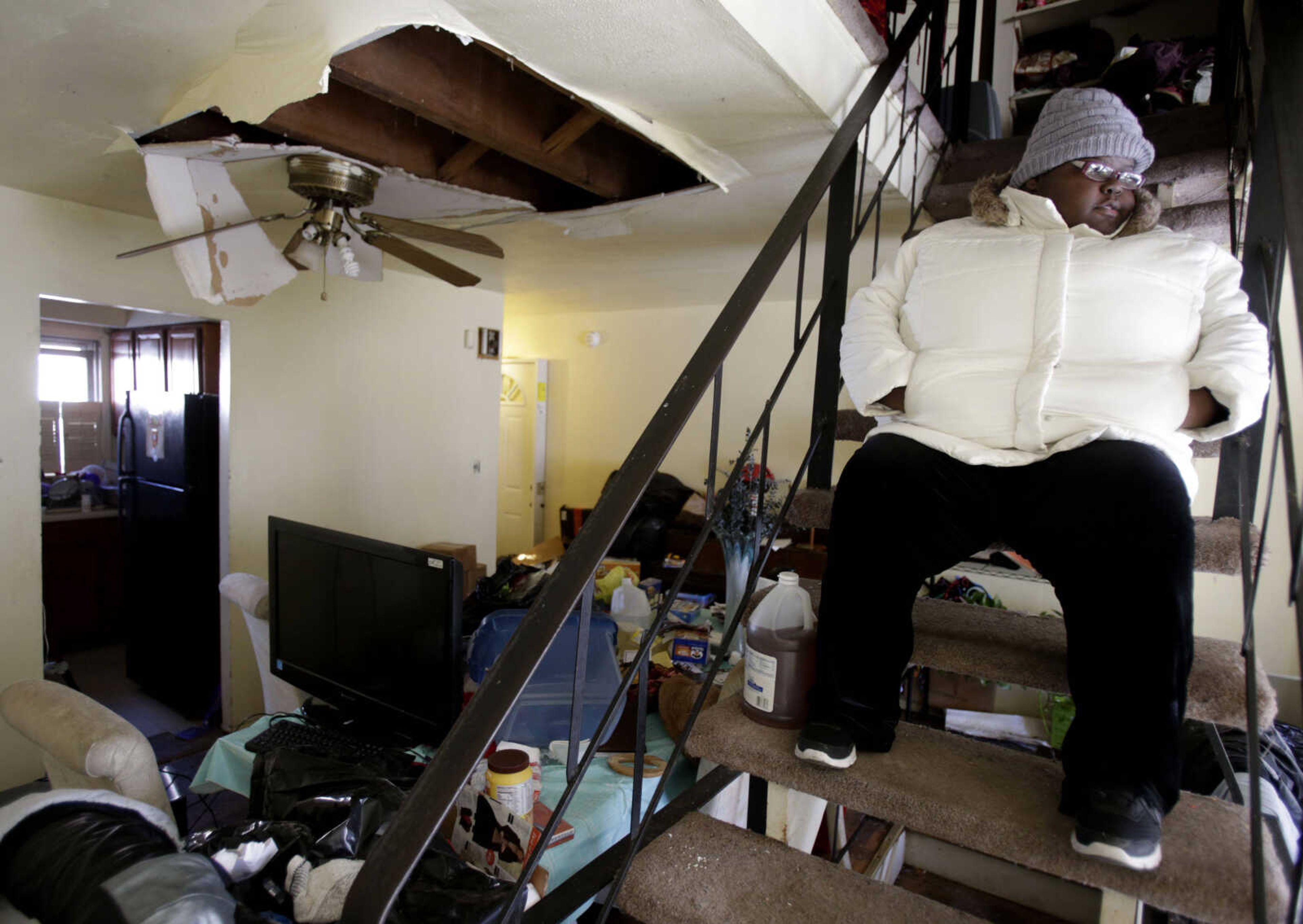 FILE - In this file photo of Jan. 24, 2013, Ayanna Diego looks over her living room while waiting for inspectors at her home, which was damaged by Superstorm Sandy, in the Rockaways section of New York. Three months after Sandy struck, thousands of storm victims in New York and New Jersey are stuck in limbo. Waiting for the heat to come on, for insurance money to come through, for loans to be approved. Waiting, in a broader sense, for their upended lives to get back to normal. (AP Photo/Seth Wenig, File)