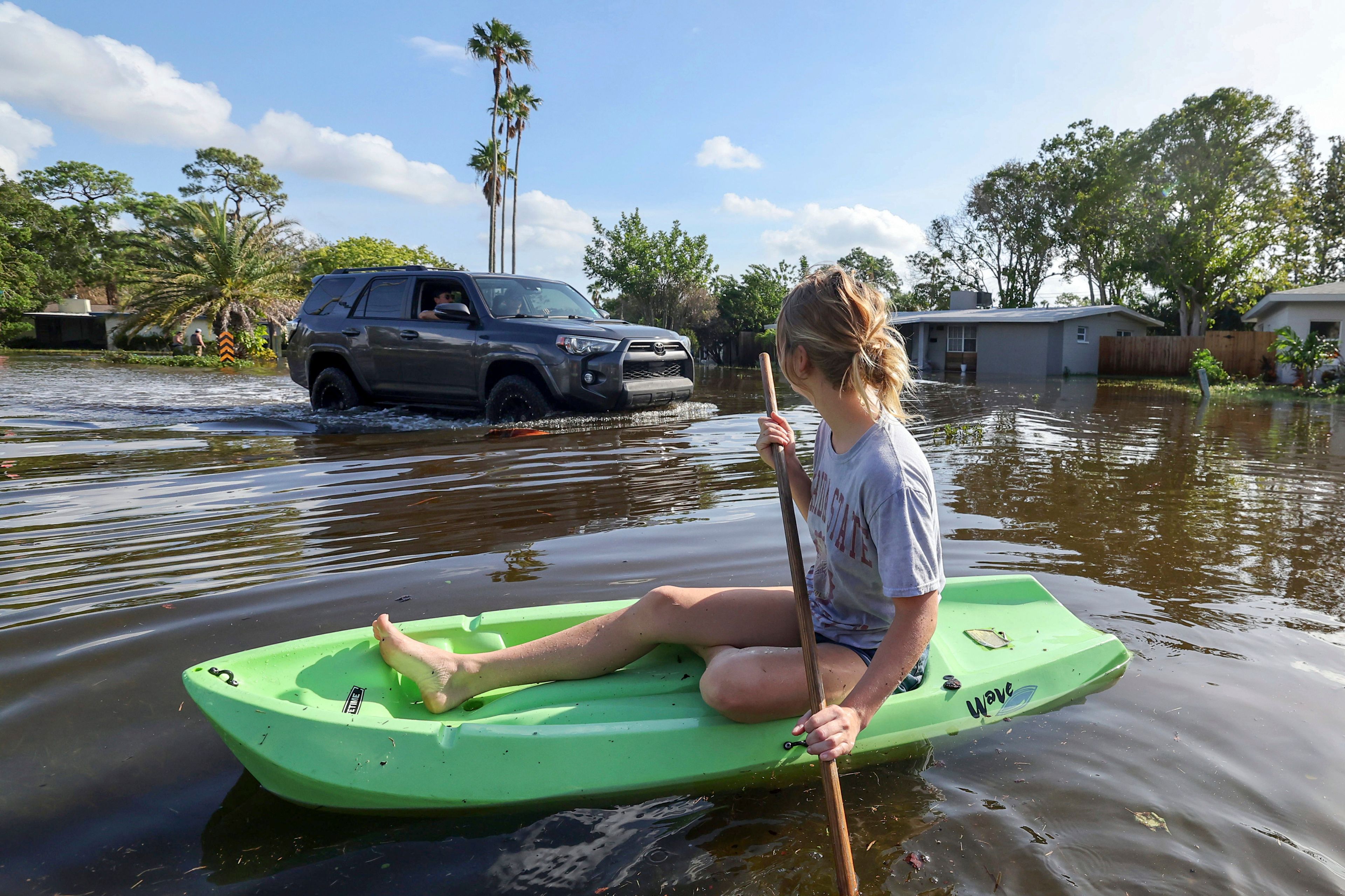 Halle Brooks kayaks down a street flooded by Hurricane Helene in the Shore Acres neighborhood Friday, Sept. 27, 2024, in St. Petersburg, Fla. (AP Photo/Mike Carlson)