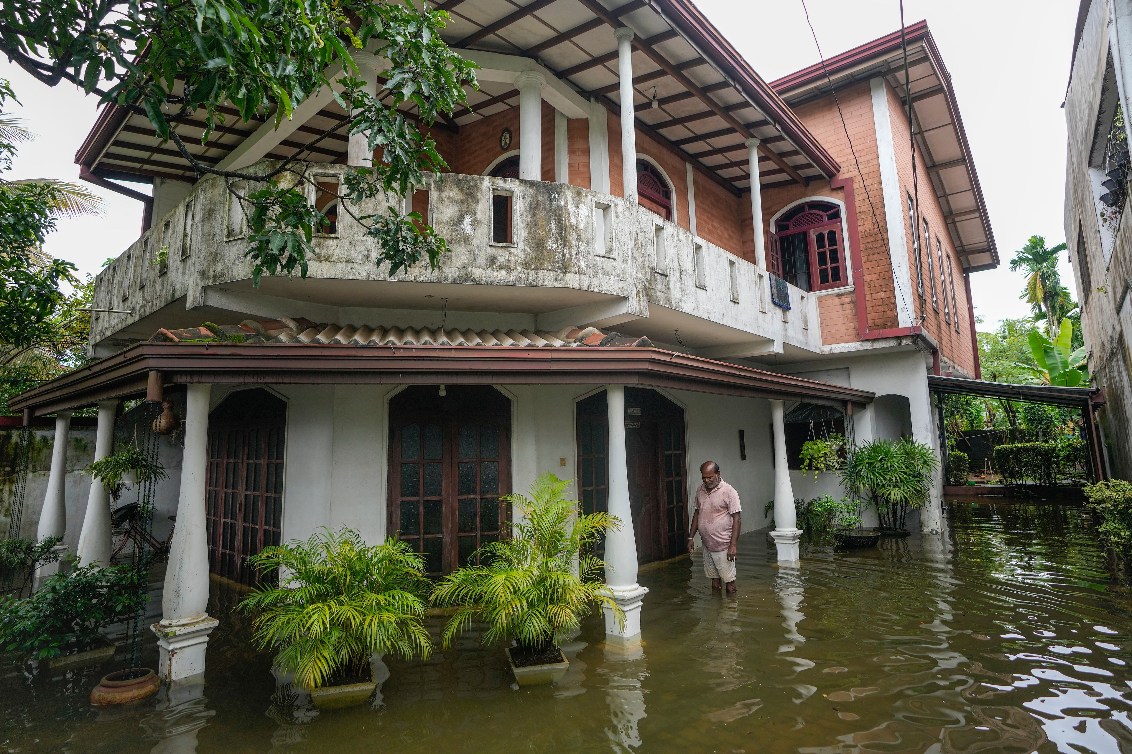 A man stands by his flooded house in Colombo, Sri Lanka, Monday, Oct. 14, 2024. (AP Photo/Eranga Jayawardena)