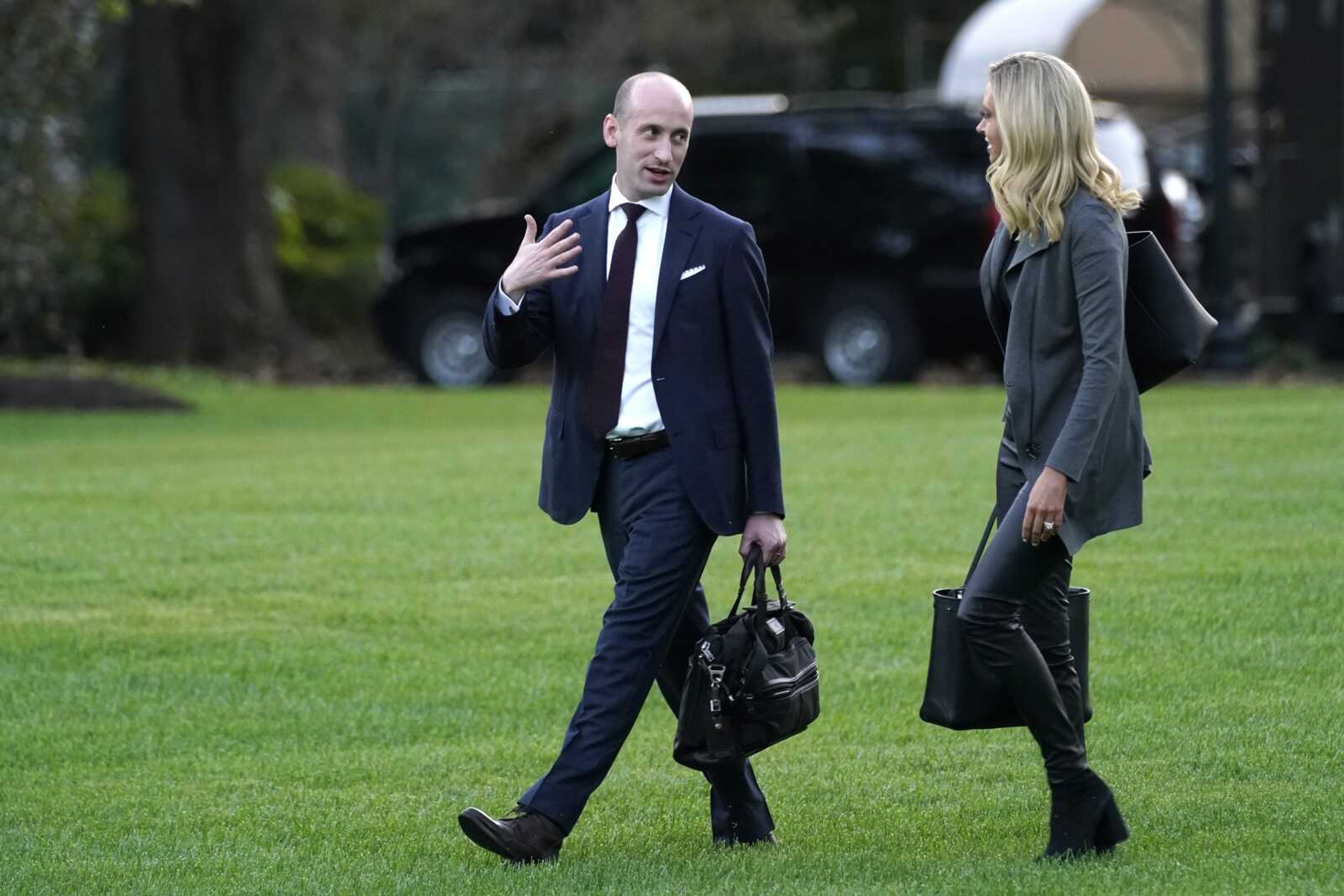 White House press secretary Kayleigh McEnany and White House senior adviser Stephen Miller walk across the South Lawn before boarding Marine One with President Donald Trump on Oct. 20, 2020, at the White House in Washington.