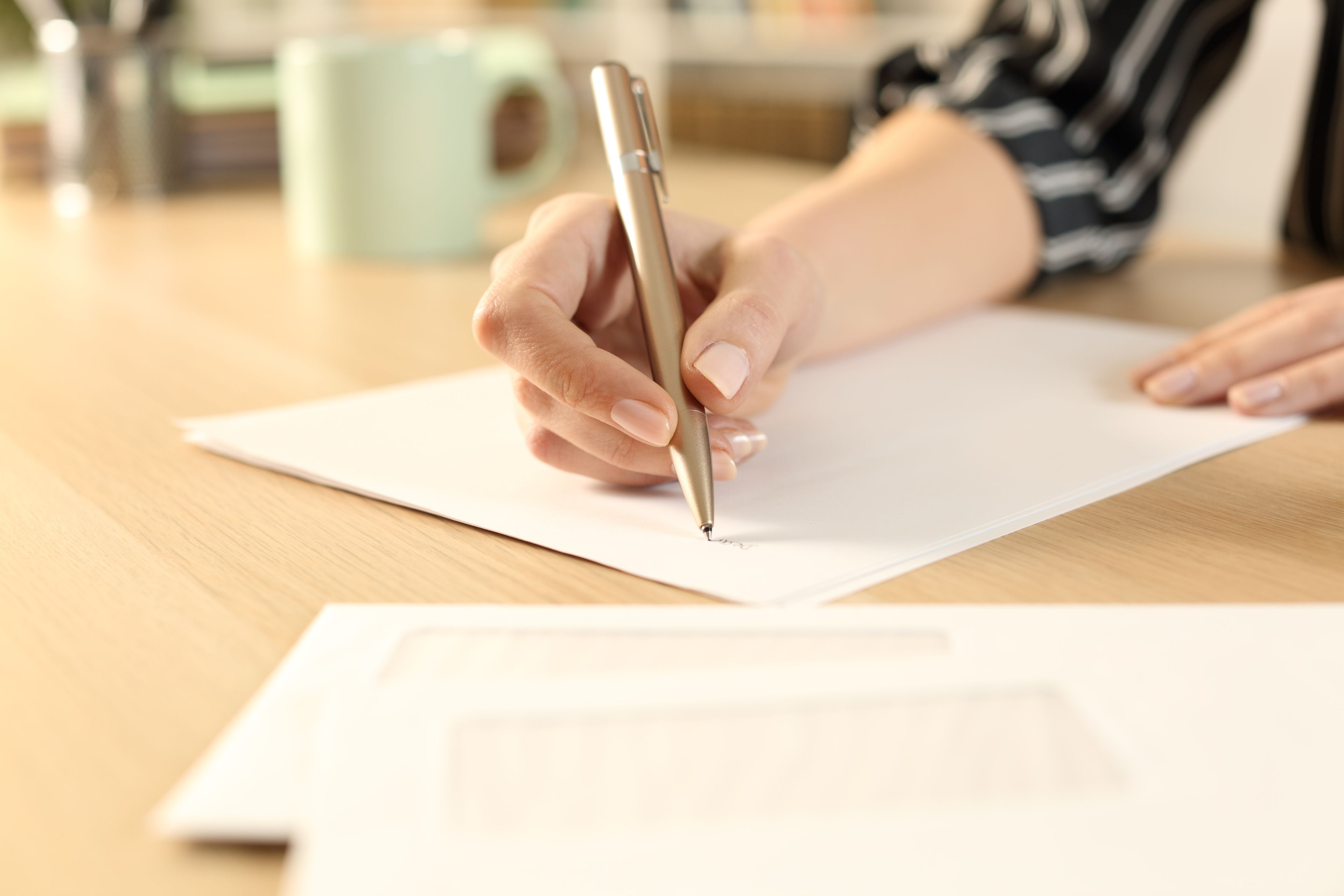 Woman hands writing letter sitting on a desk