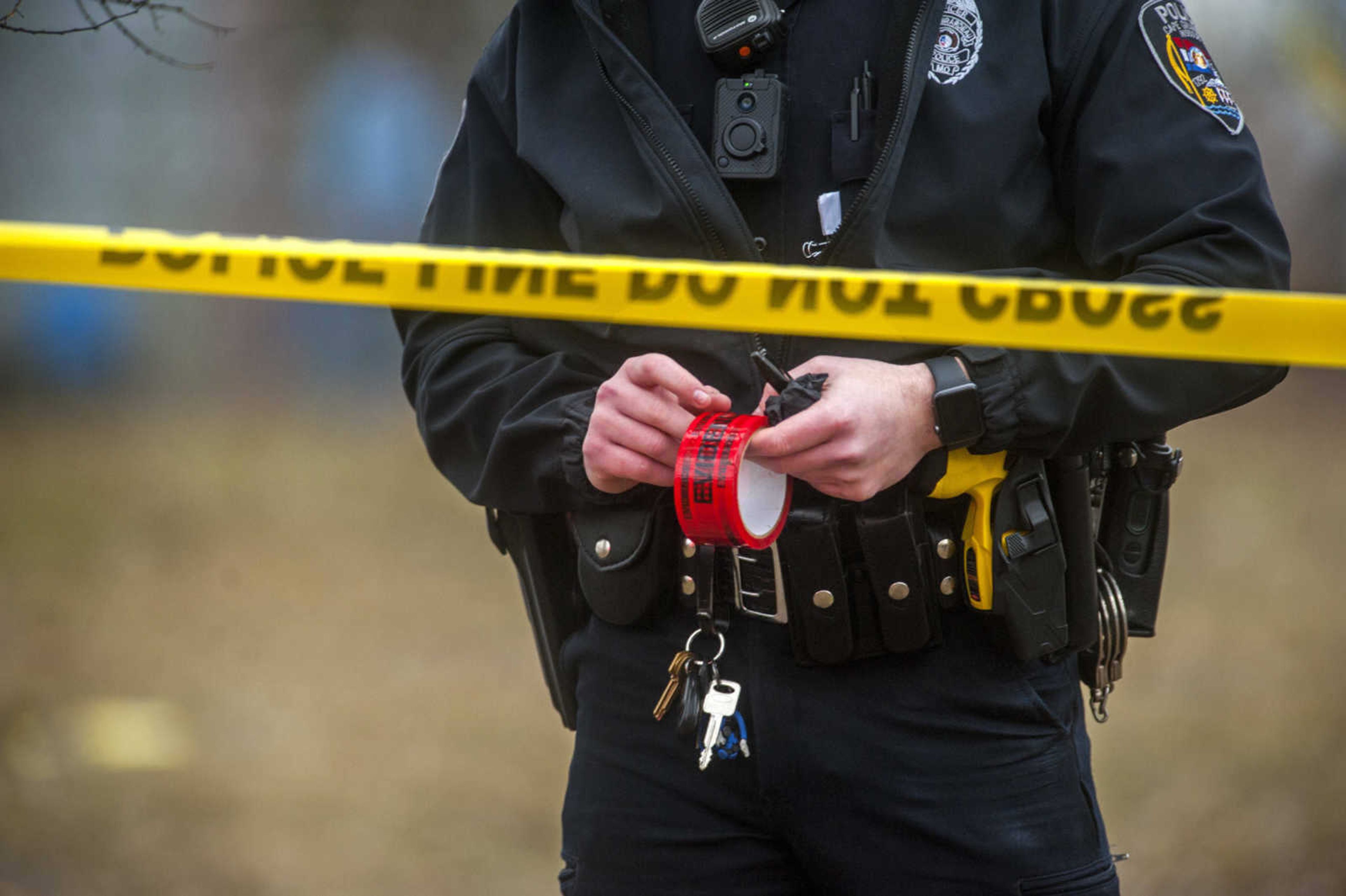 A police officer holds a roll of evidence tape while investigating a shooting that left one man dead in a car in the 900 block of S. Benton Street in Cape Girardeau Monday, Feb. 4, 2019. (Tyler Graef ~ Southeast Missourian)
