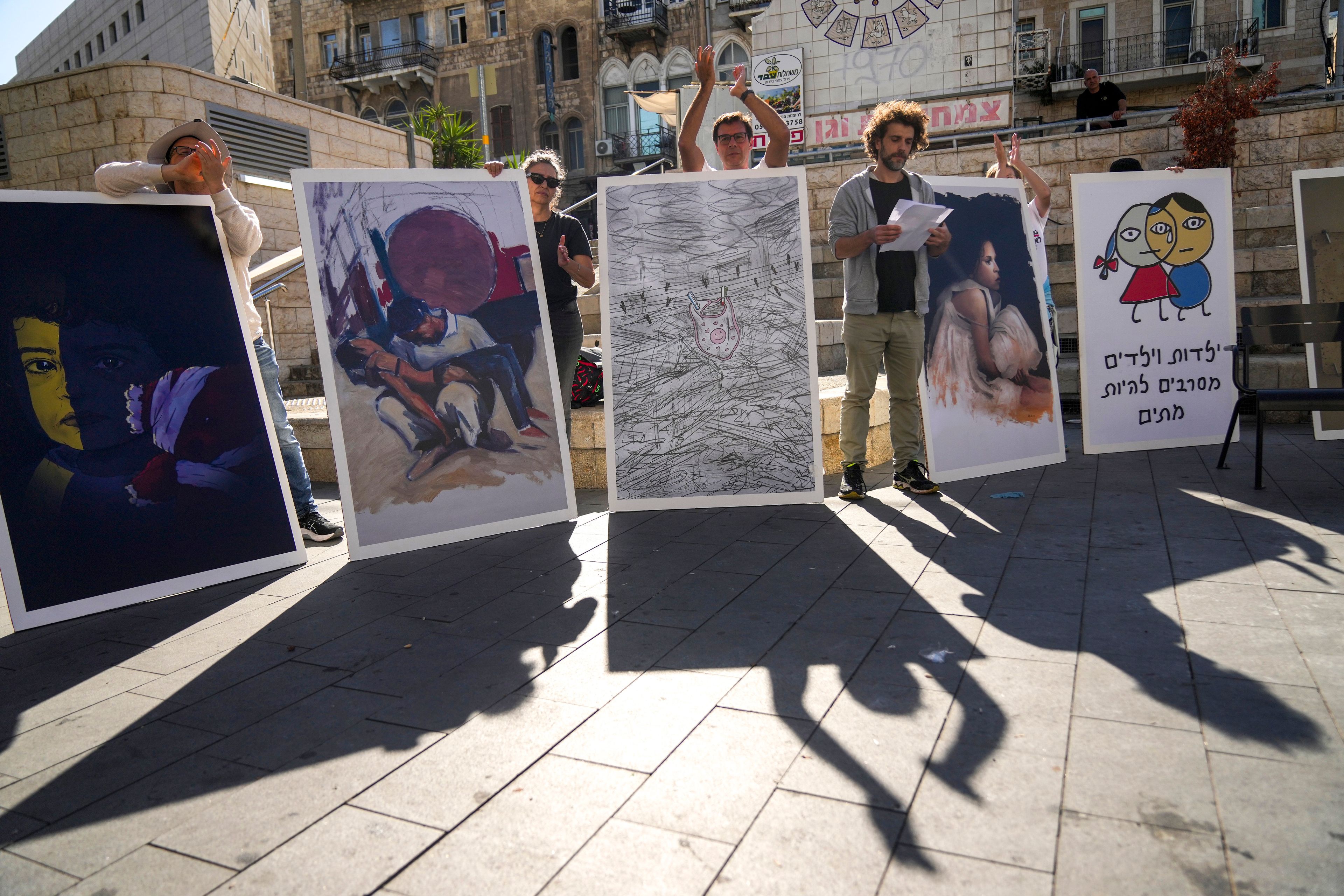 People hold boards during a protest against Israel's military operations in the Gaza Strip and Lebanon and calling for the release of hostages held in the Gaza Strip by the Hamas militant group, in Haifa, Israel, Friday, Nov. 22, 2024. Placard on the right reads “Children refuse to die”. (AP Photo/Francisco Seco)