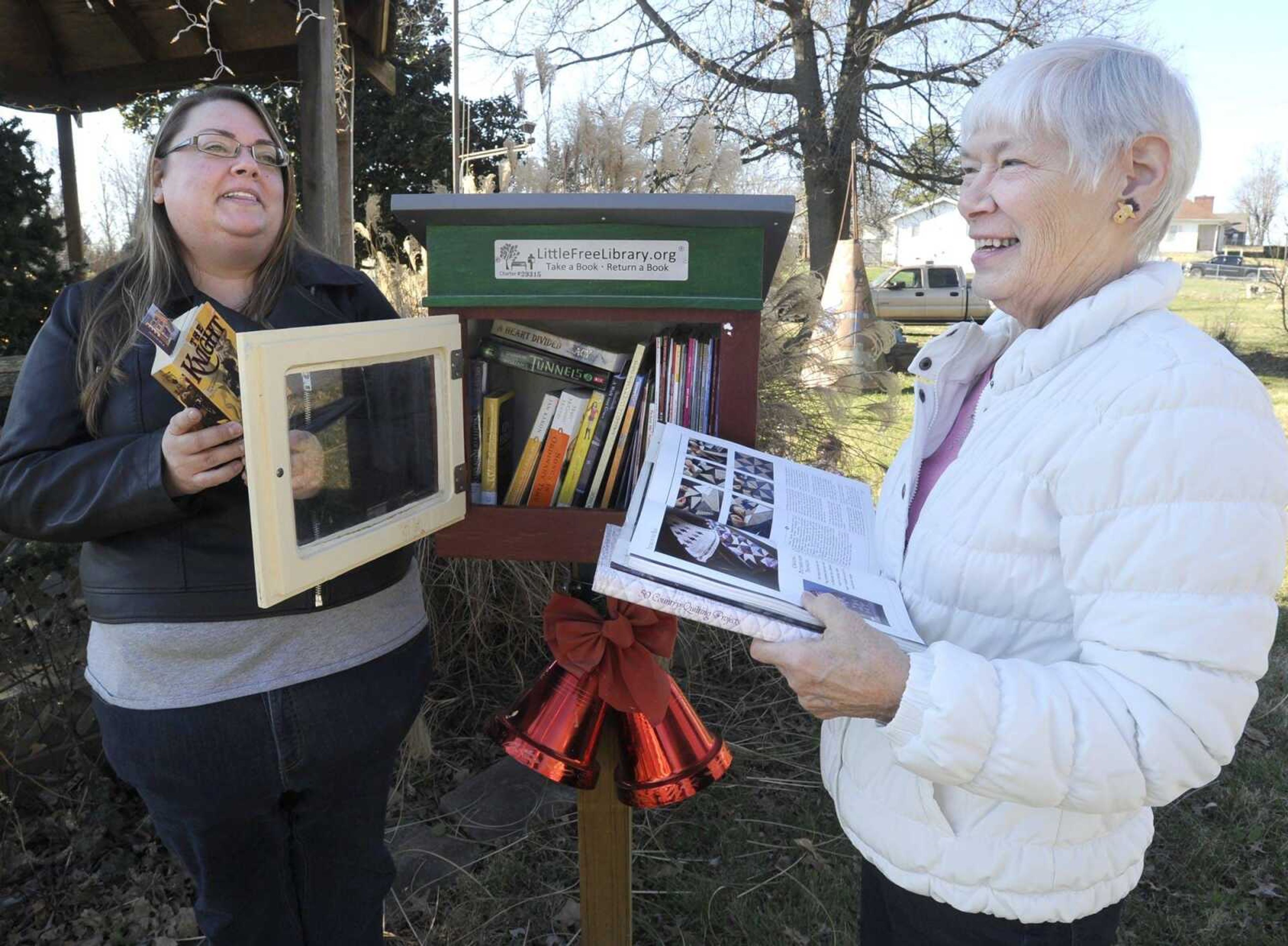 Cutline-File Credit:Becky LaClair, left, and Doris Dace show the Little Free Library in Pocahontas, Missouri. (Fred Lynch)