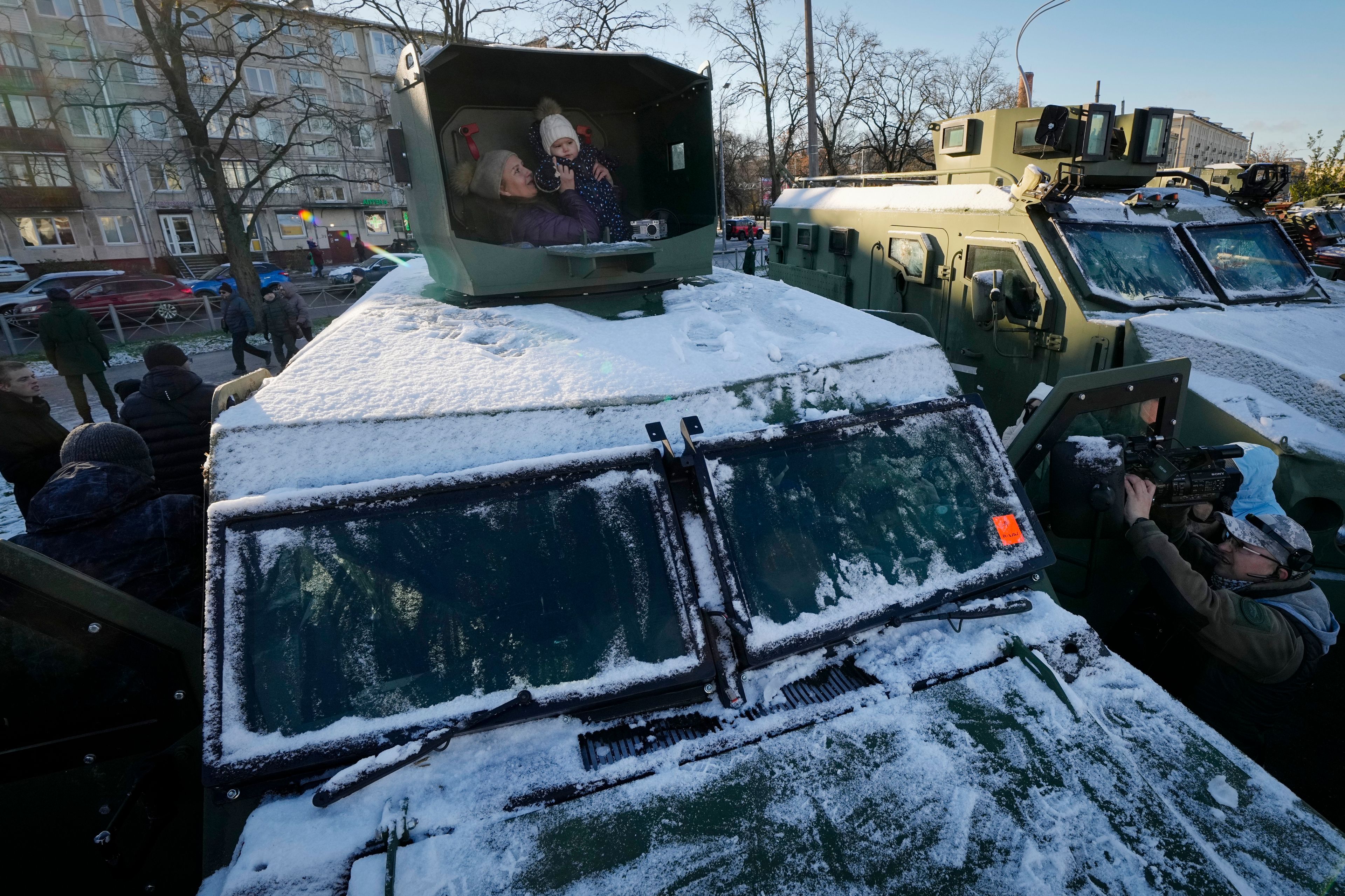 A woman and her child sit in an Ukrainian military vehicle at an exhibition featuring military equipment captured from Kyiv forces during the fighting in Ukraine, during Russia's National Unity Day in St. Petersburg, Russia, Monday, Nov. 4, 2024. (AP Photo/Dmitri Lovetsky)